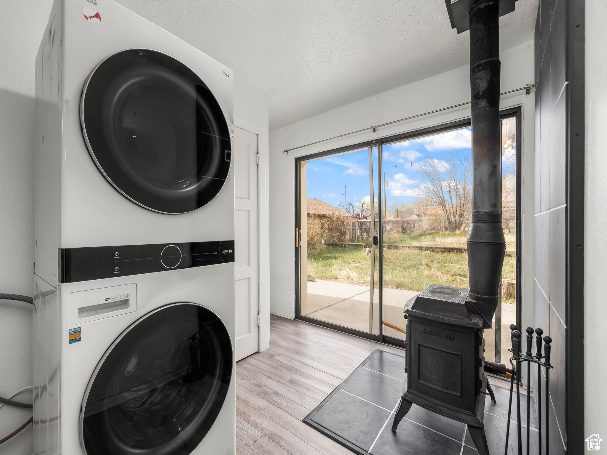 Clothes washing area with light hardwood / wood-style floors and stacked washer / drying machine