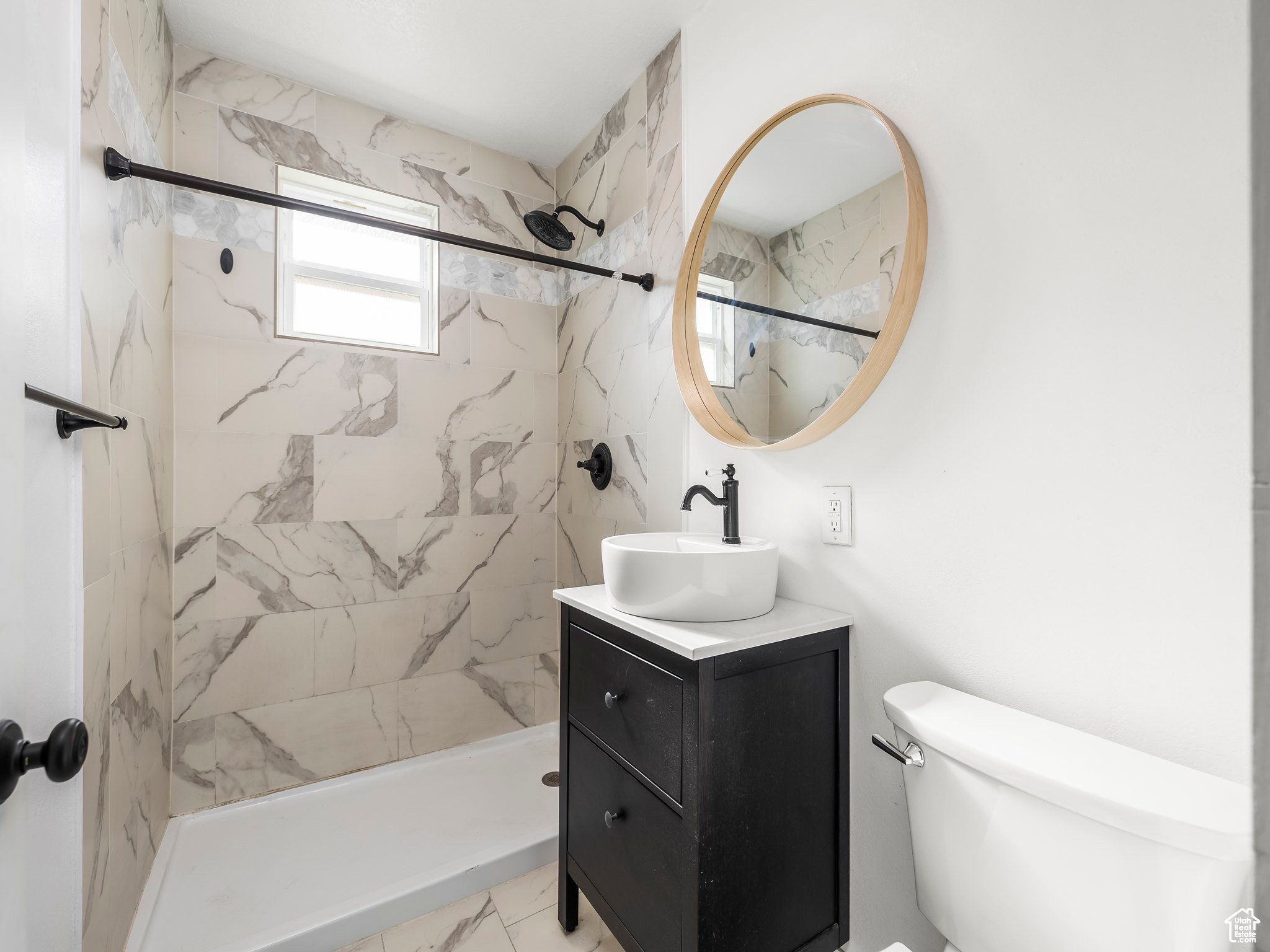 Bathroom with tiled shower, vanity, and toilet