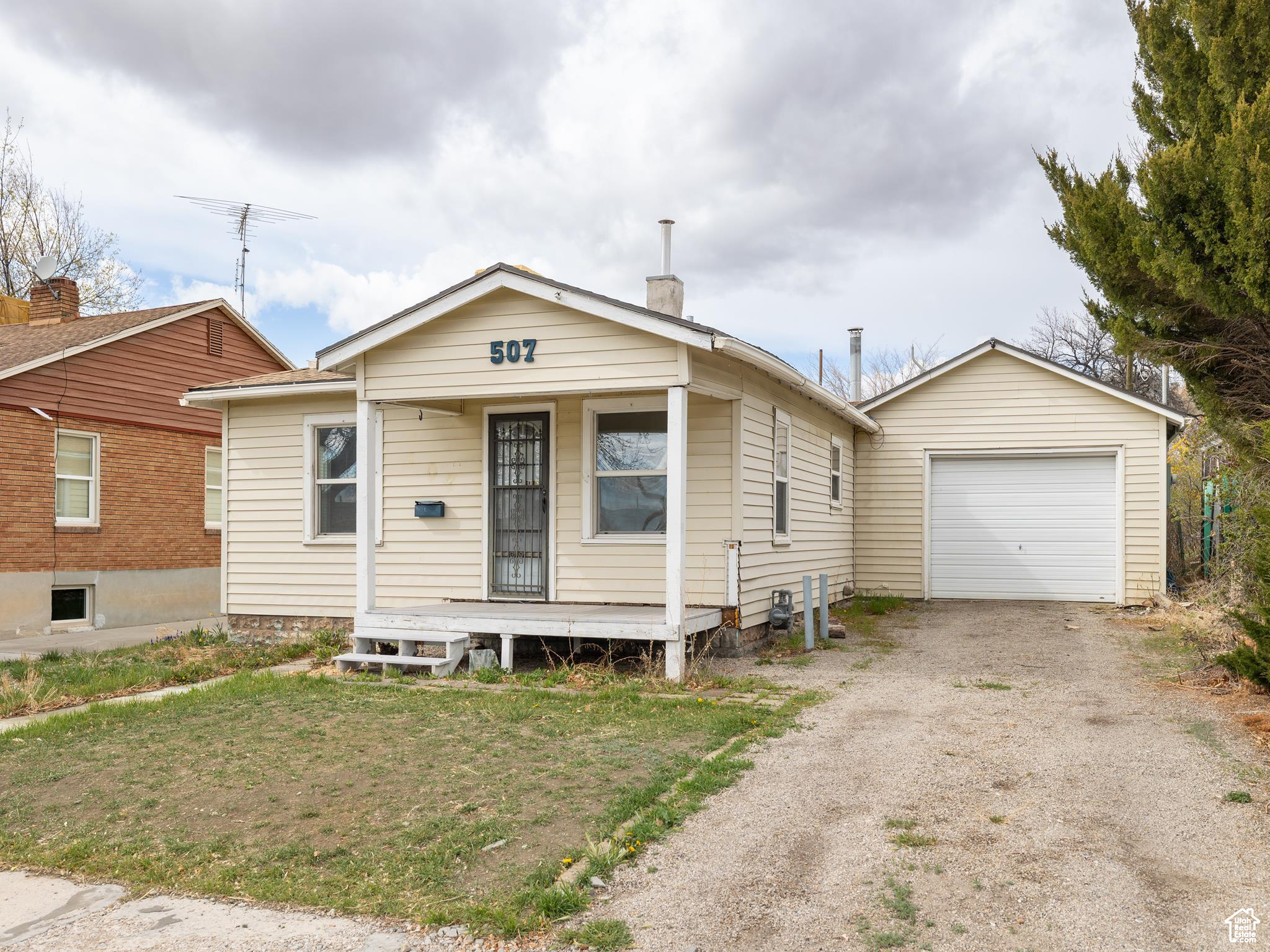 View of front of property with a porch, a front yard, and a garage