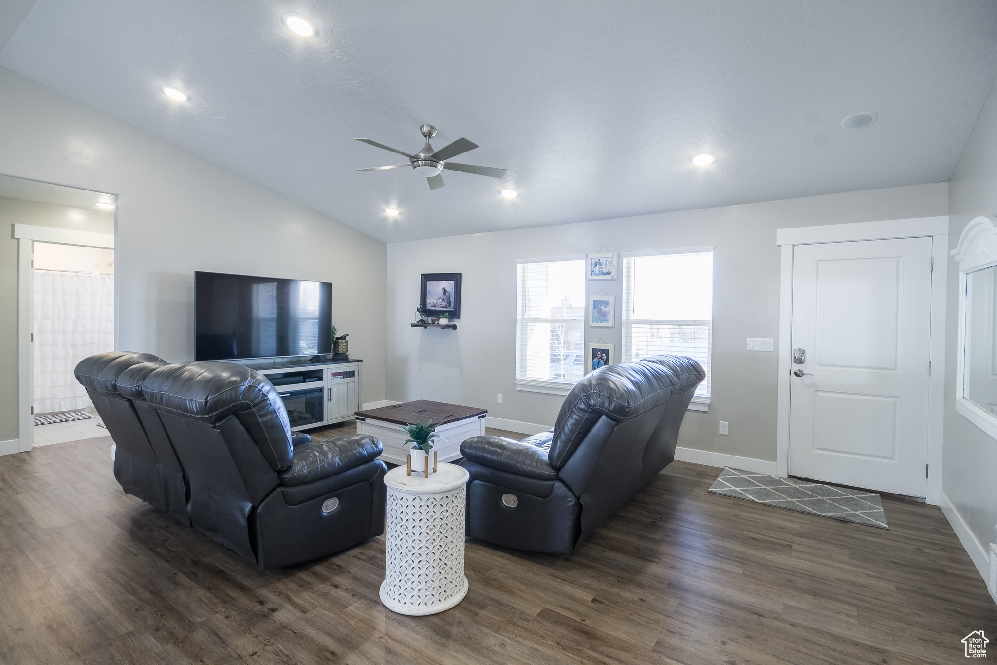 Living room with ceiling fan, dark wood-type flooring, and lofted ceiling