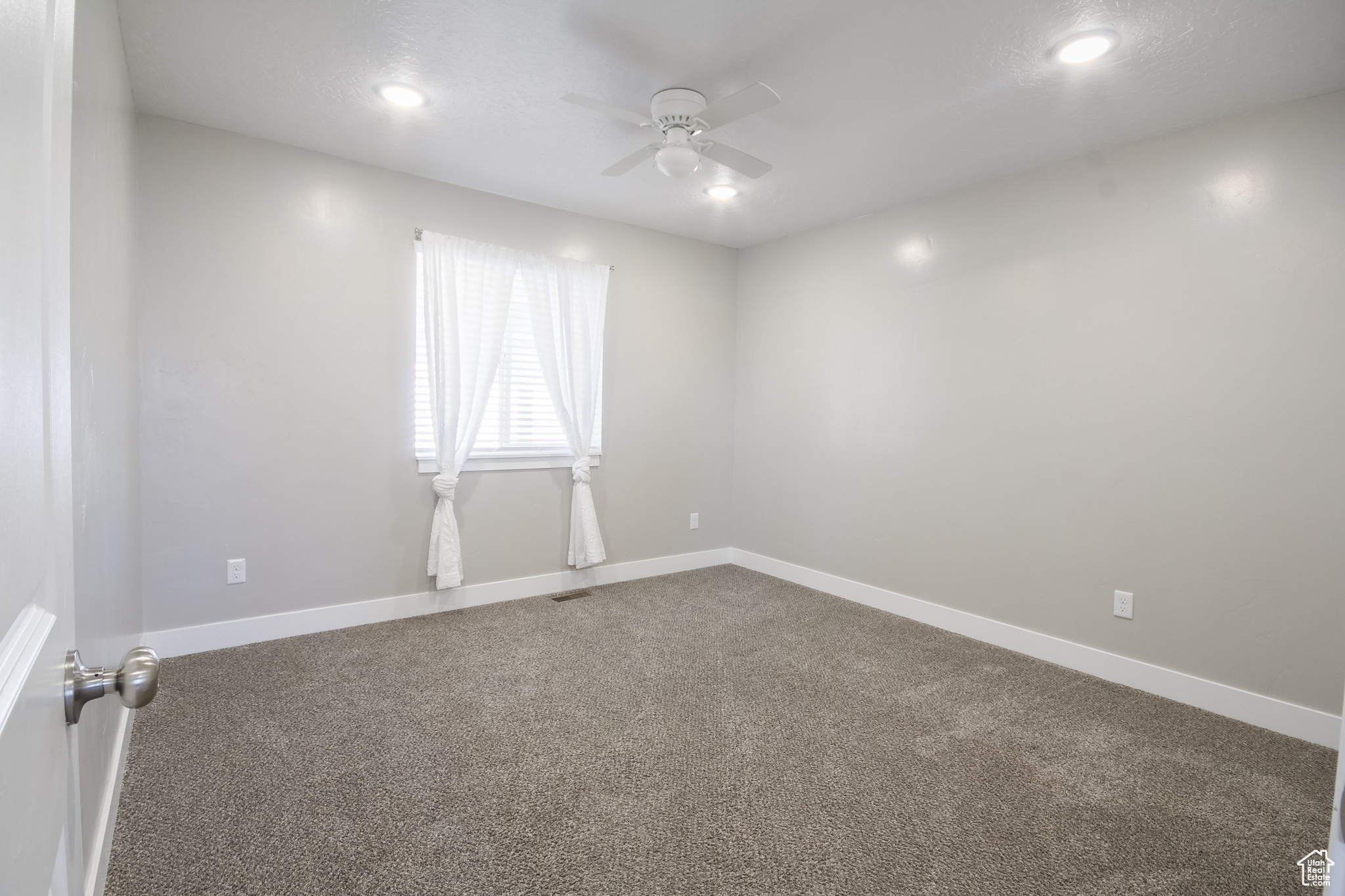 Carpeted empty room with ceiling fan