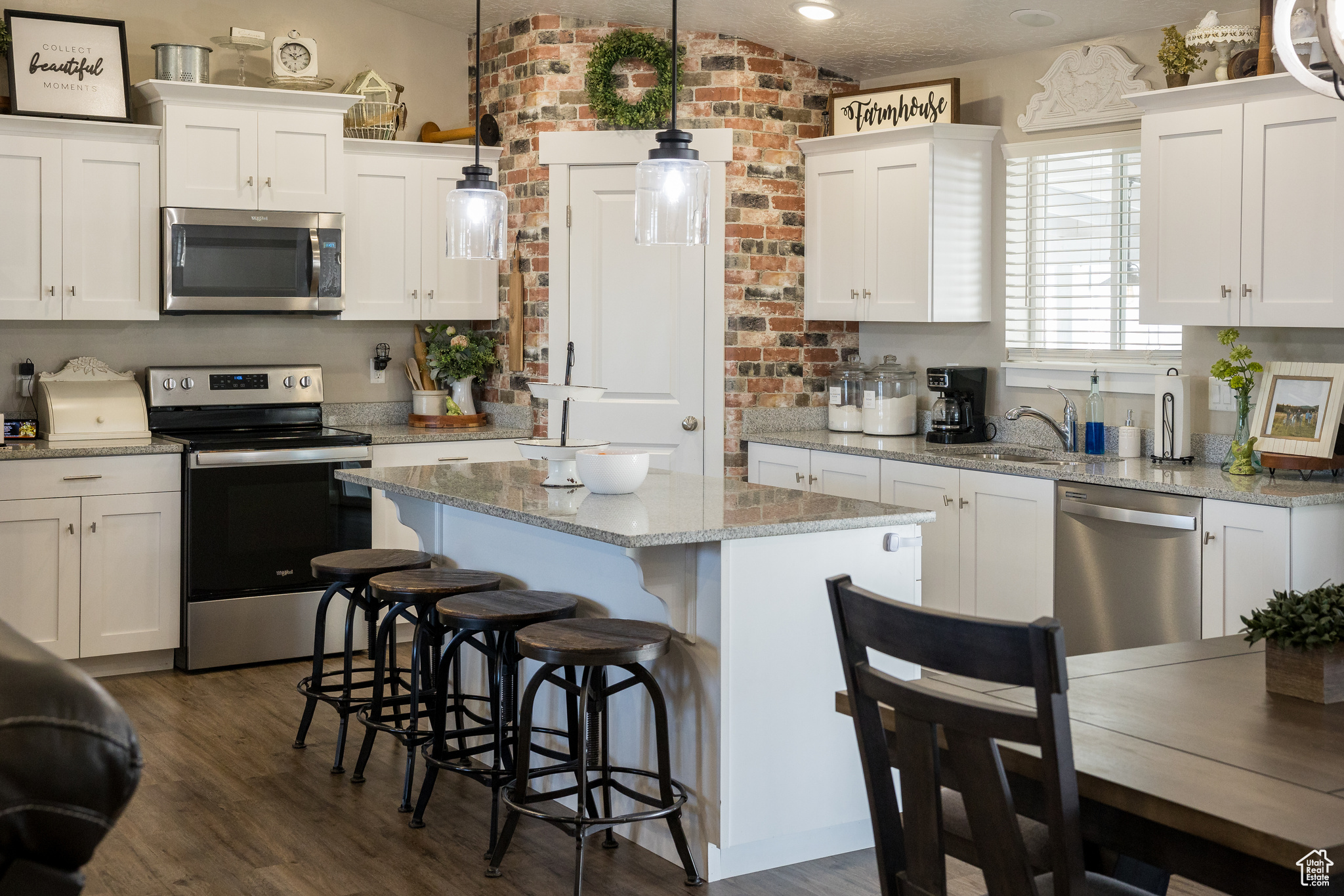 Kitchen with white cabinets, appliances with stainless steel finishes, a center island, and a breakfast bar area