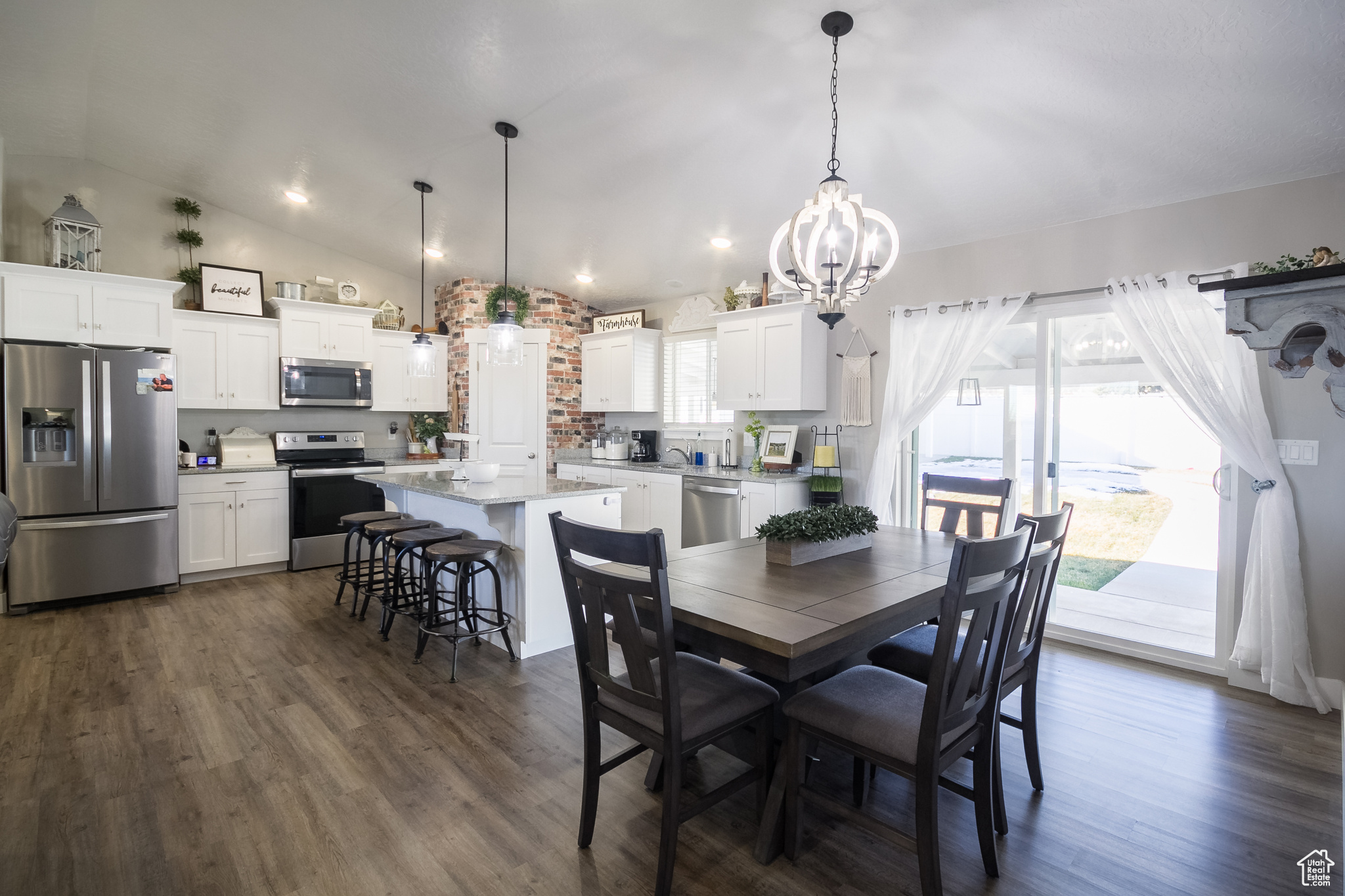 Dining space with dark wood-type flooring, an inviting chandelier, and lofted ceiling