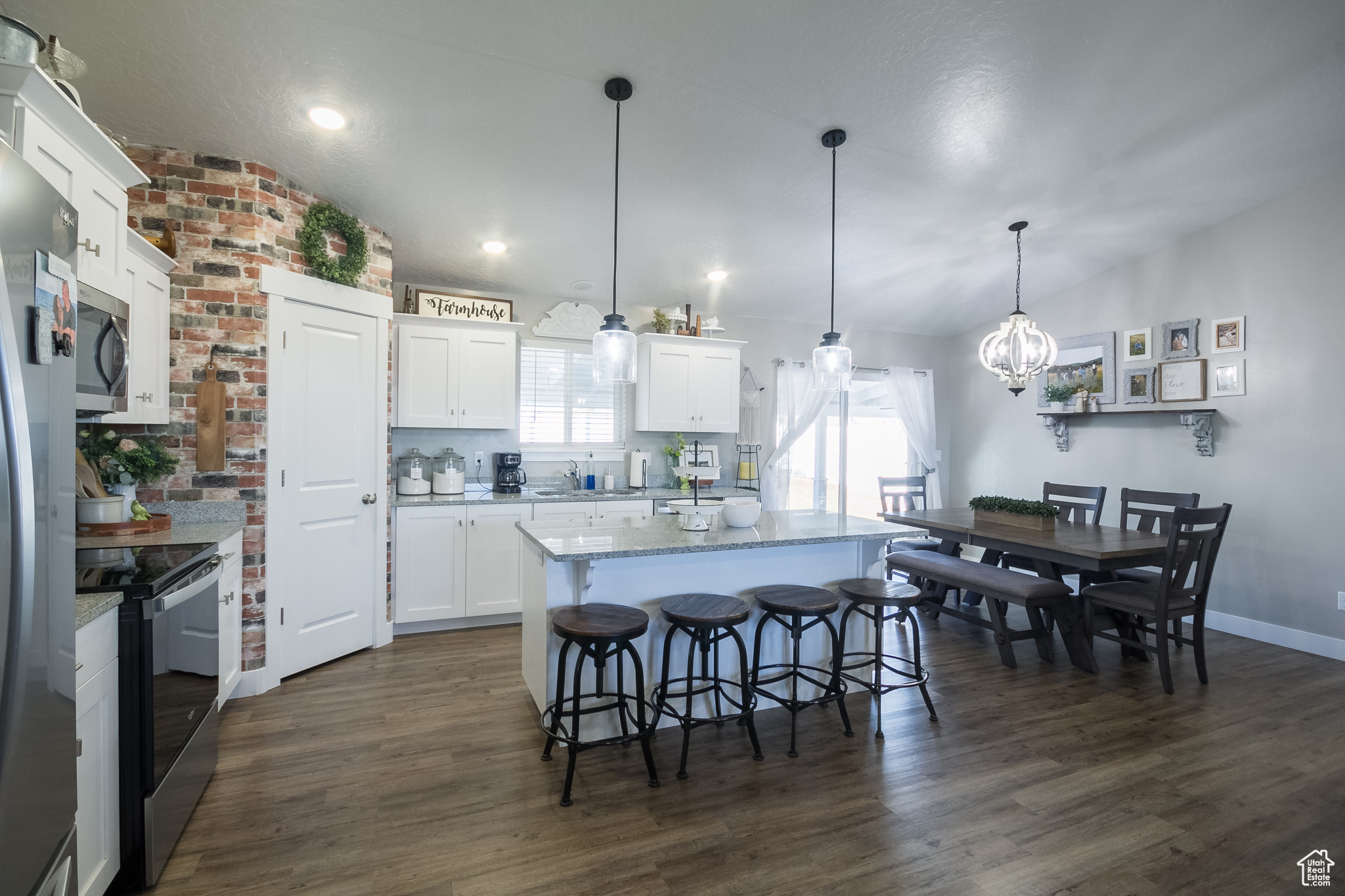 Kitchen with white cabinetry, pendant lighting, a kitchen island, and stainless steel appliances