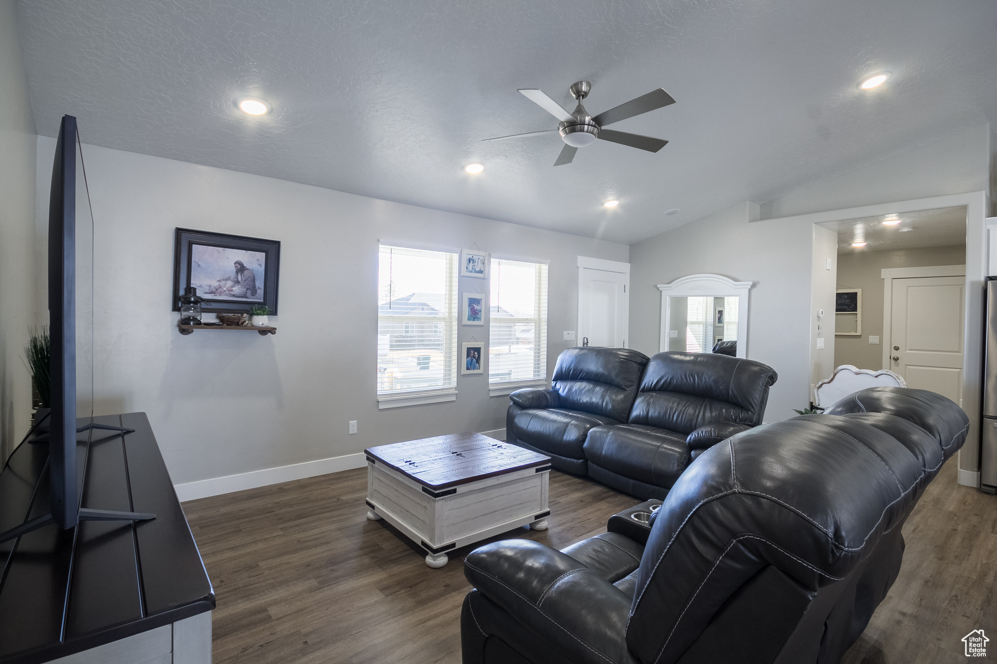 Living room with dark hardwood / wood-style floors, ceiling fan, and lofted ceiling