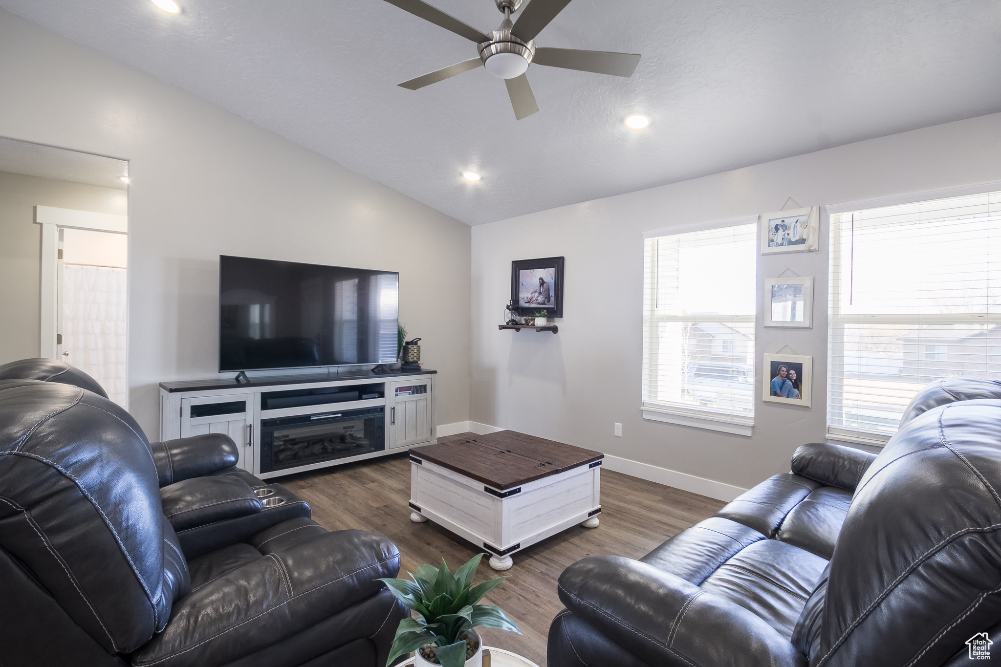 Living room with dark hardwood / wood-style floors, ceiling fan, and lofted ceiling