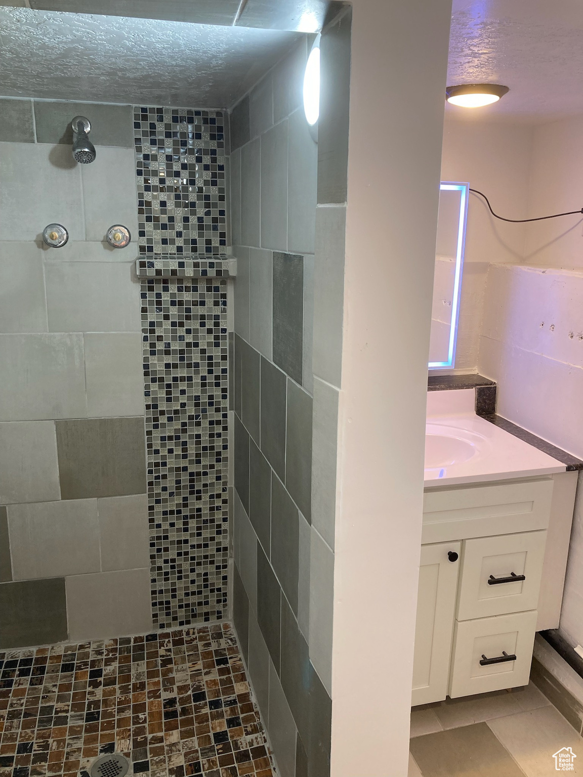 Bathroom featuring vanity, a textured ceiling, and tiled shower