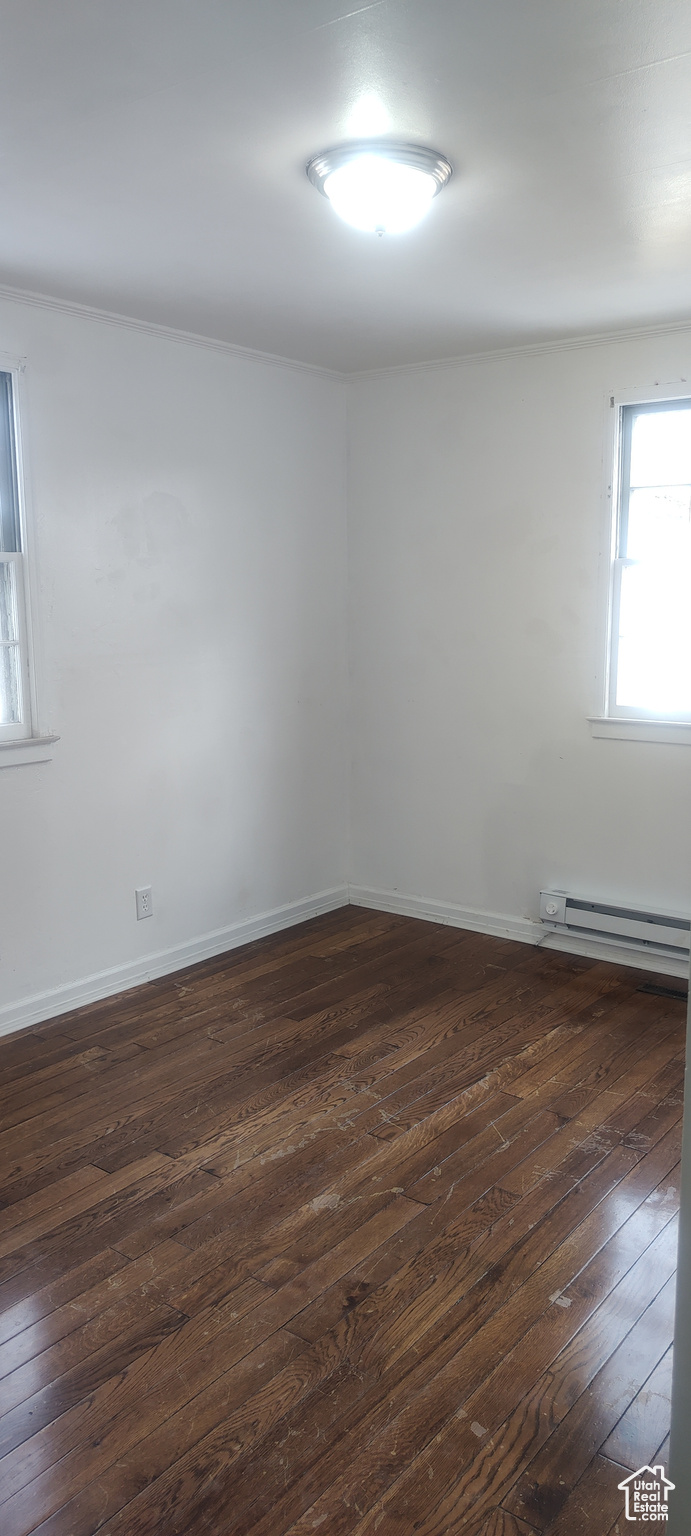 Unfurnished room with dark hardwood / wood-style floors and baseboard heating