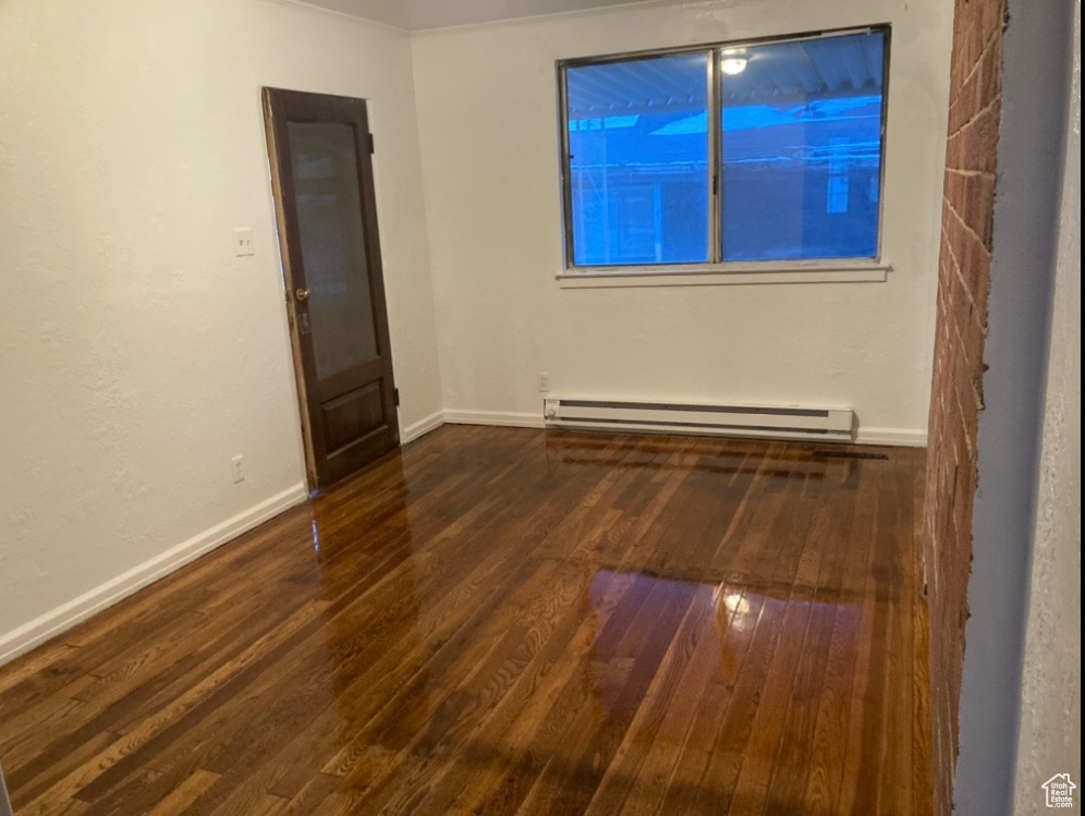 Spare room featuring a baseboard radiator and dark hardwood / wood-style floors