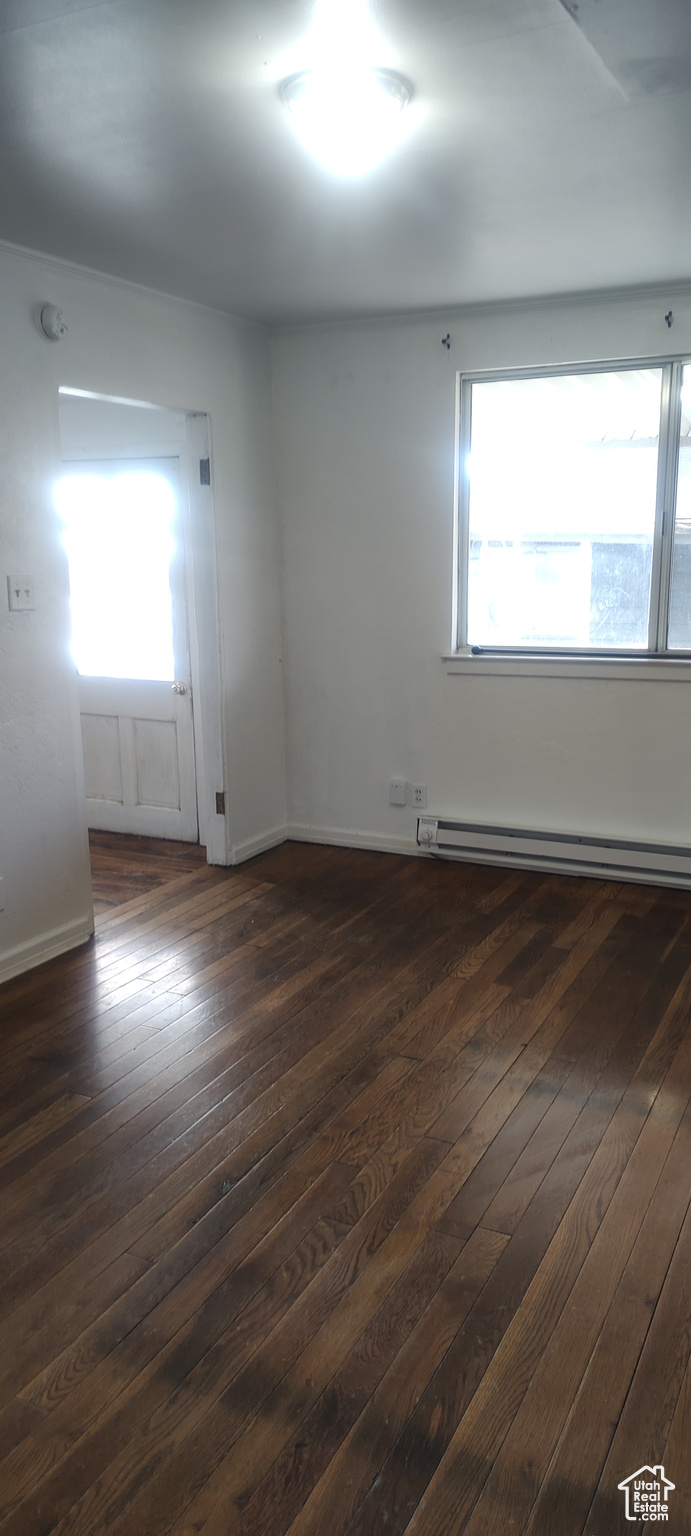 Spare room with dark wood-type flooring and a baseboard radiator