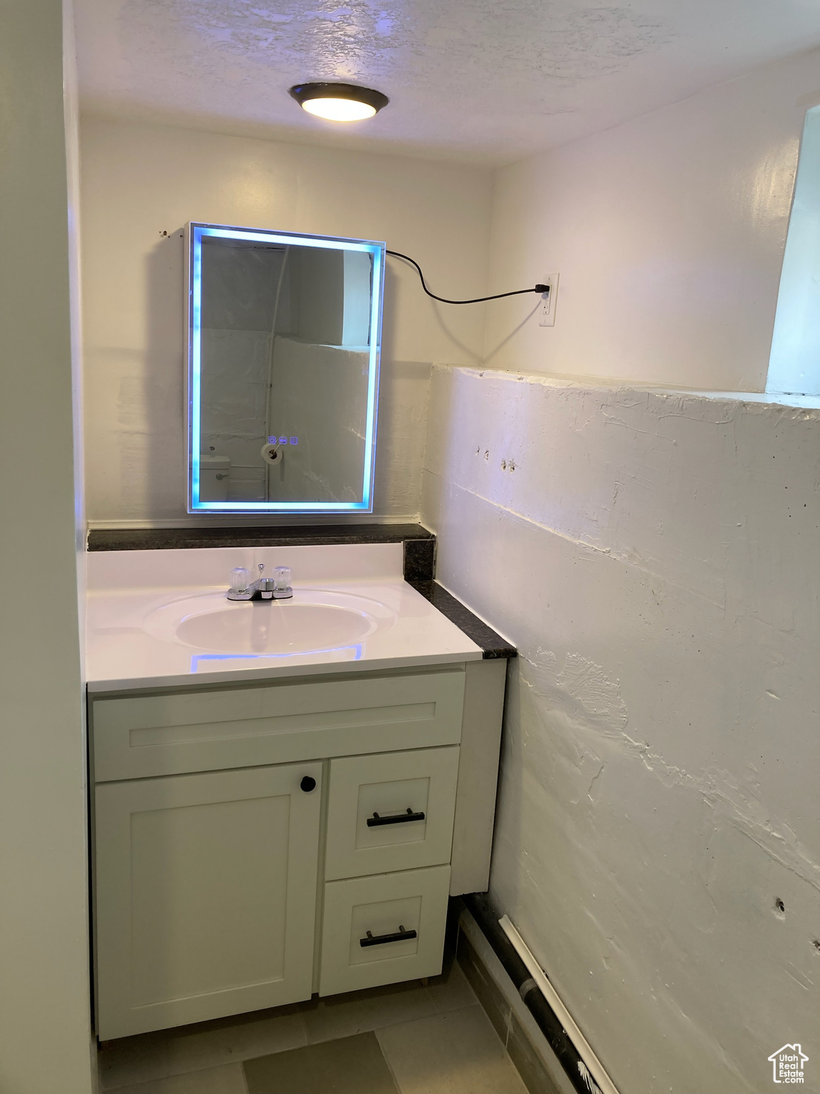 Bathroom featuring tile patterned flooring, vanity, and a textured ceiling