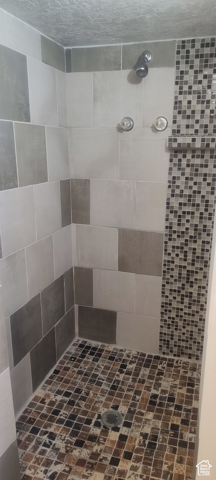 Bathroom featuring a tile shower and a textured ceiling