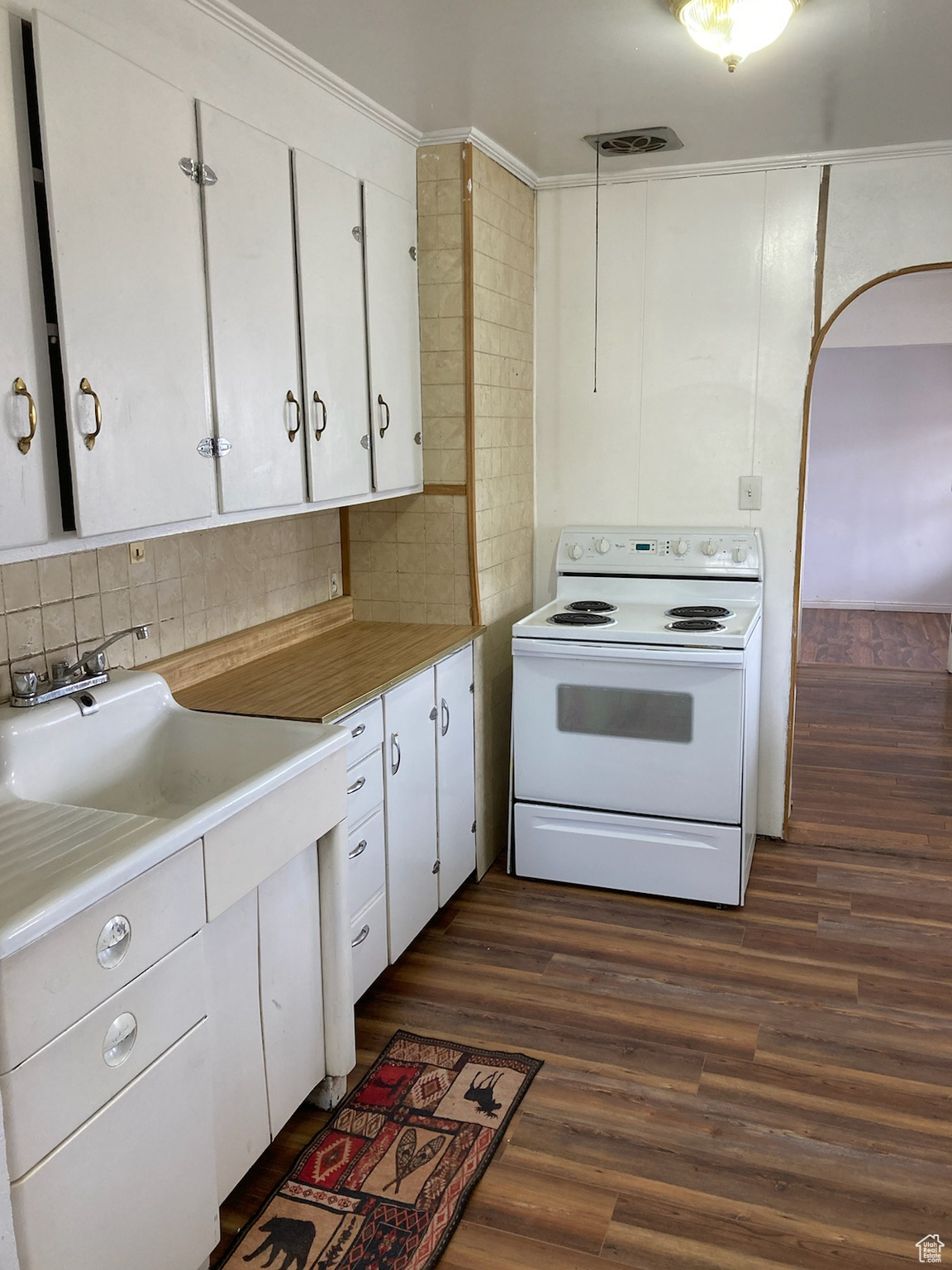 Kitchen with sink, dark hardwood / wood-style floors, white range with electric stovetop, backsplash, and white cabinets