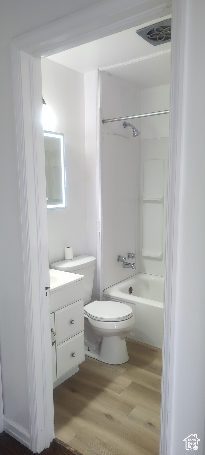 Full bathroom with hardwood / wood-style flooring, vanity, toilet, and washtub / shower combination