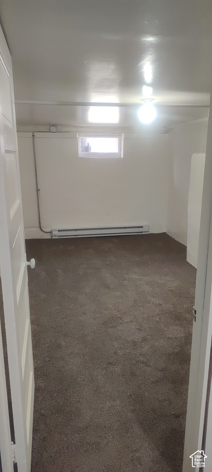 Basement featuring dark carpet and a baseboard radiator