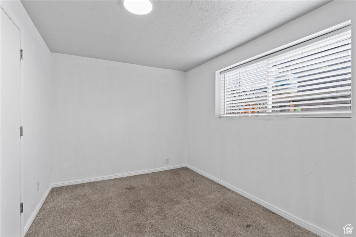 Carpeted spare room featuring a textured ceiling