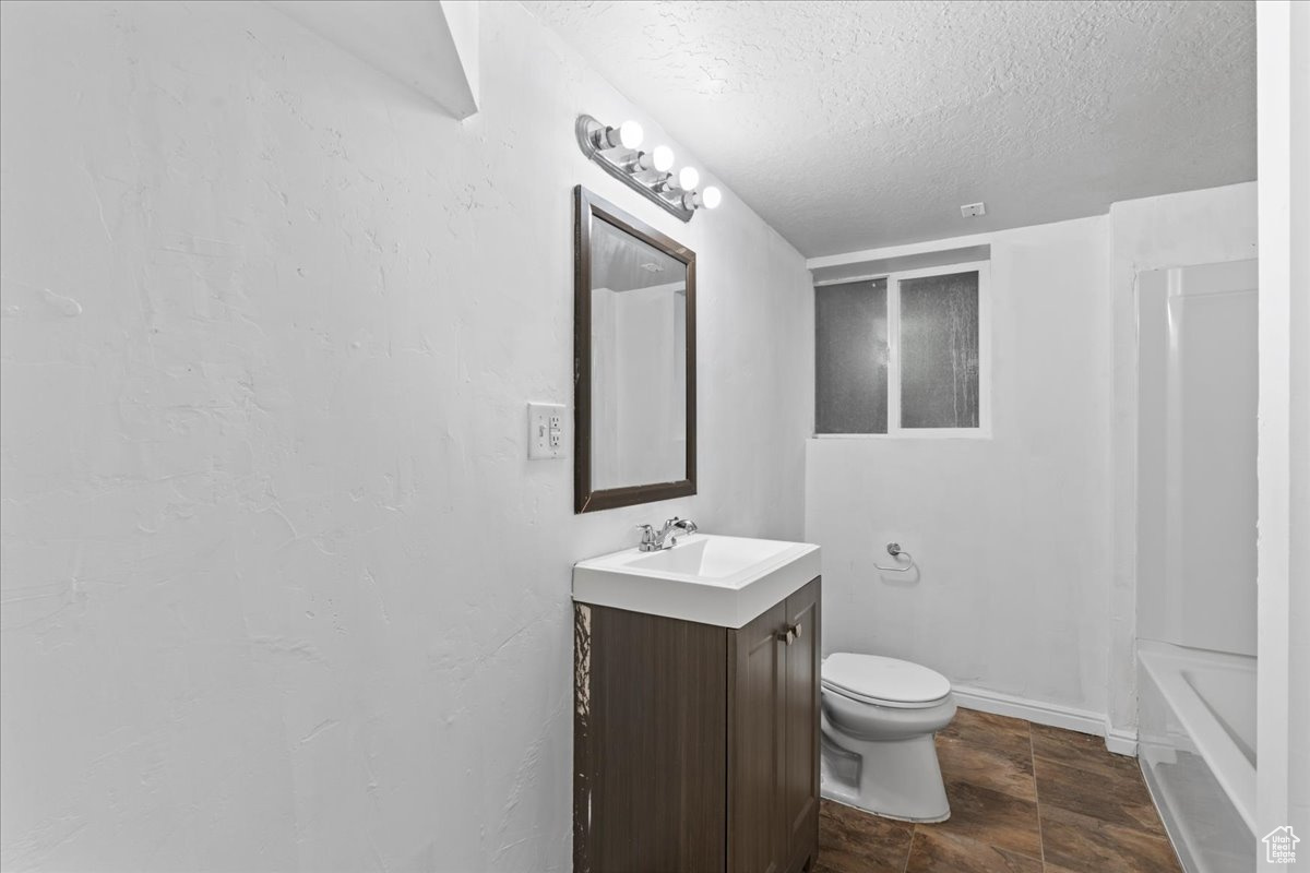 Bathroom with vanity, a textured ceiling, and toilet