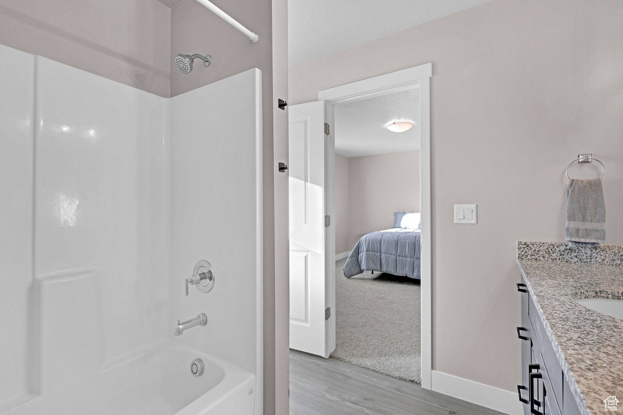 Bathroom with shower / bathing tub combination, vanity, and hardwood / wood-style floors