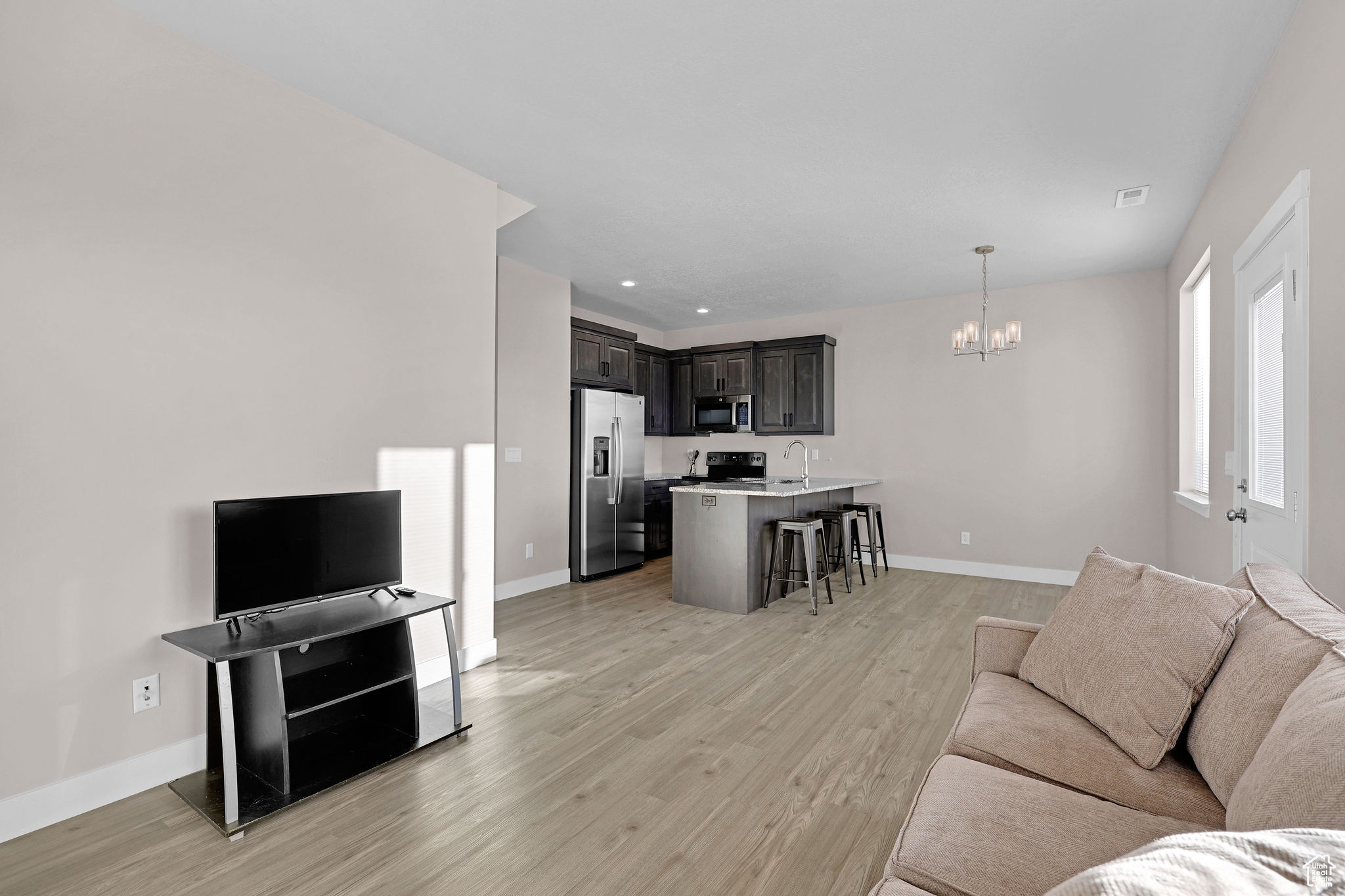 Living room with sink, light hardwood / wood-style flooring, and an inviting chandelier