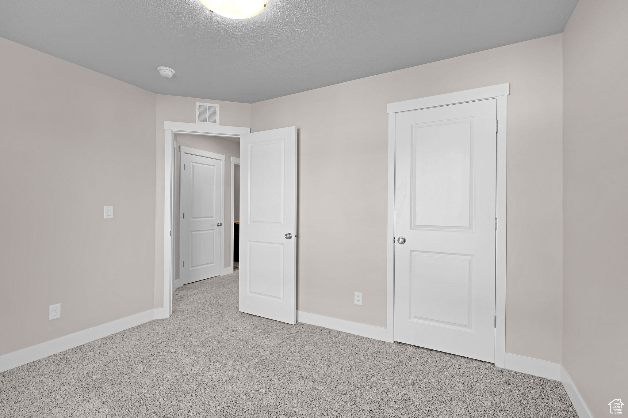 Unfurnished bedroom with carpet floors and a textured ceiling