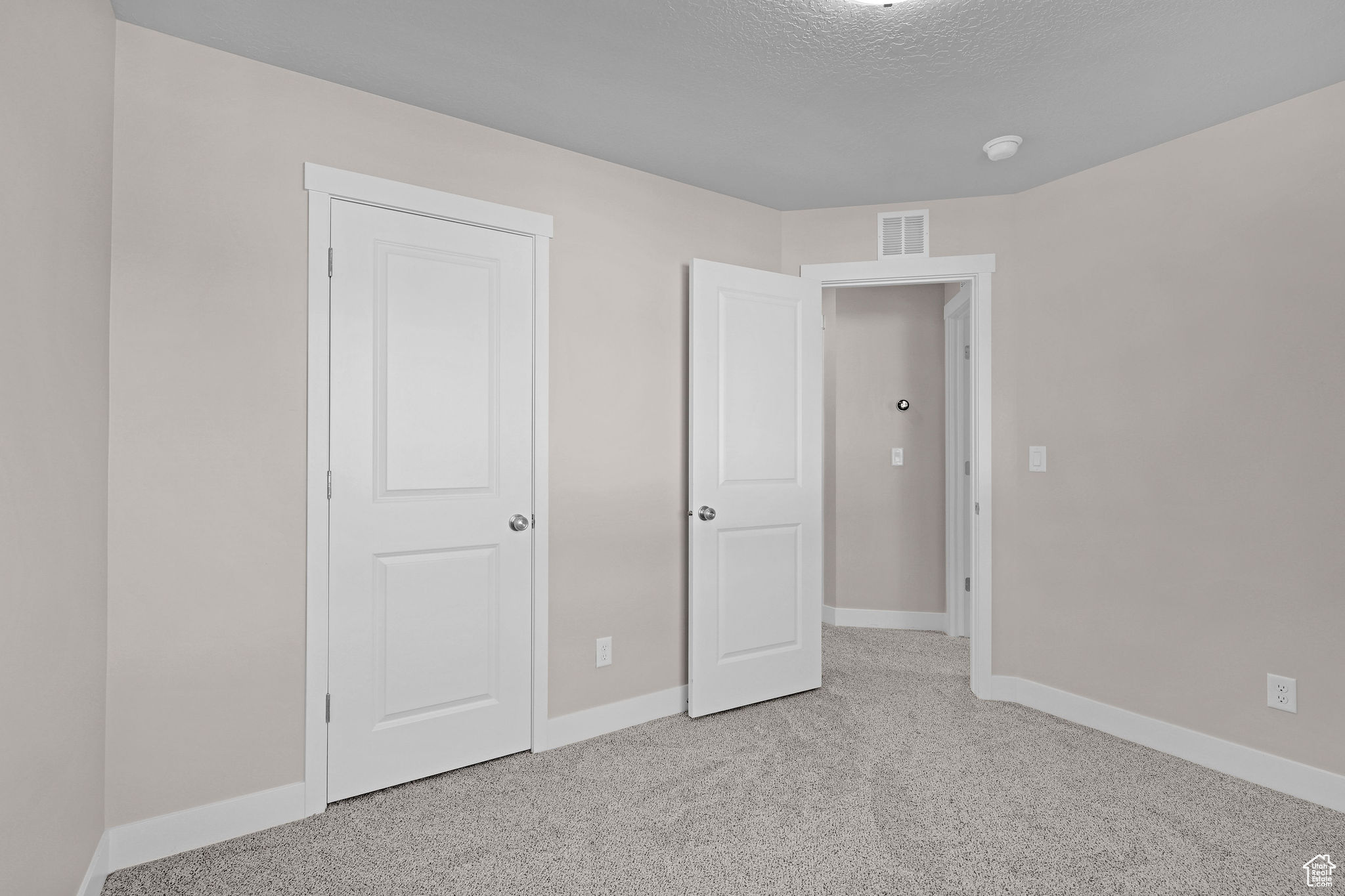 Unfurnished bedroom with light carpet and a textured ceiling