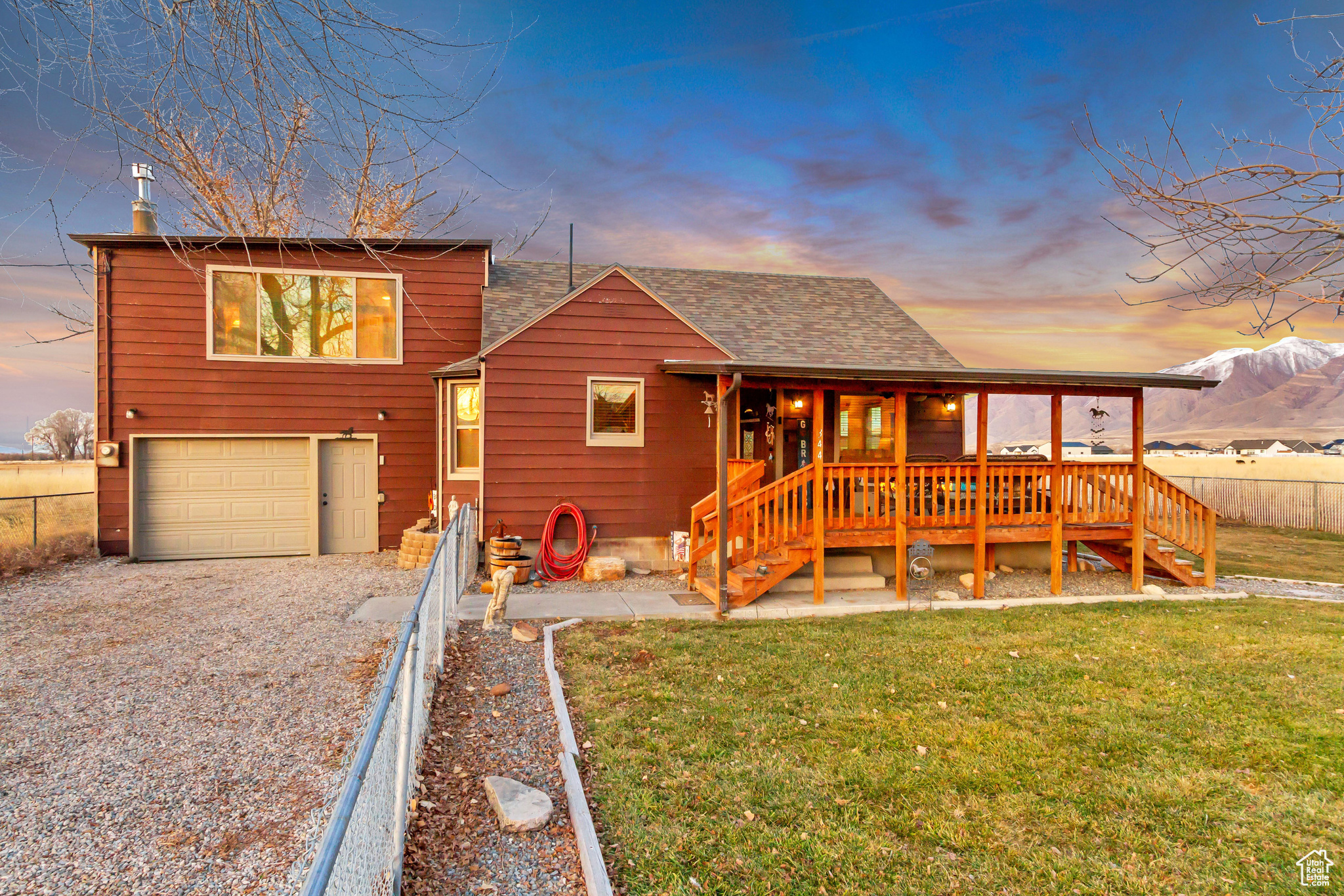 View of front facade featuring a garage, a yard, and a deck