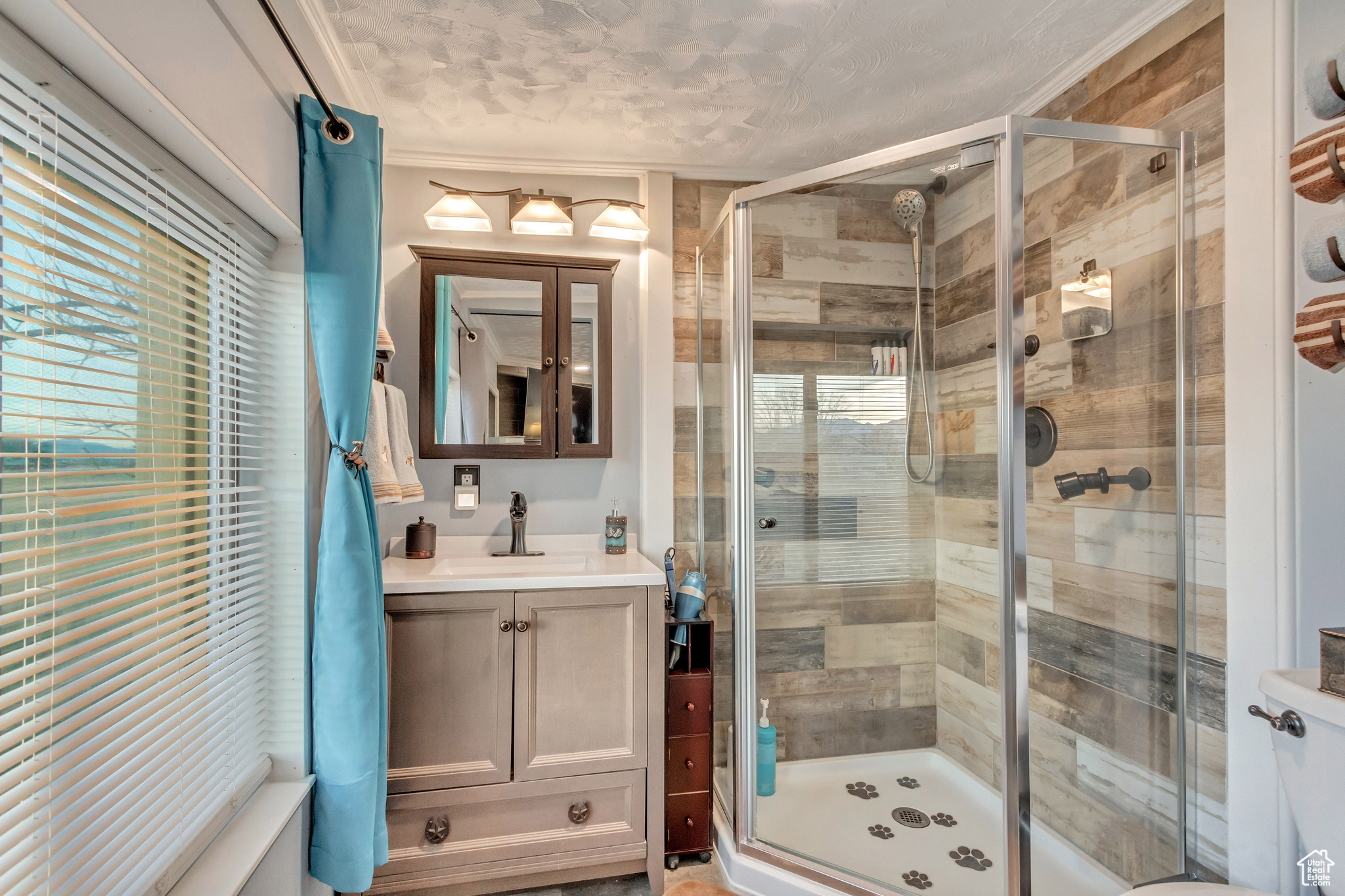 Bathroom with a tile shower with body jets, vanity, and a healthy amount of sunlight,