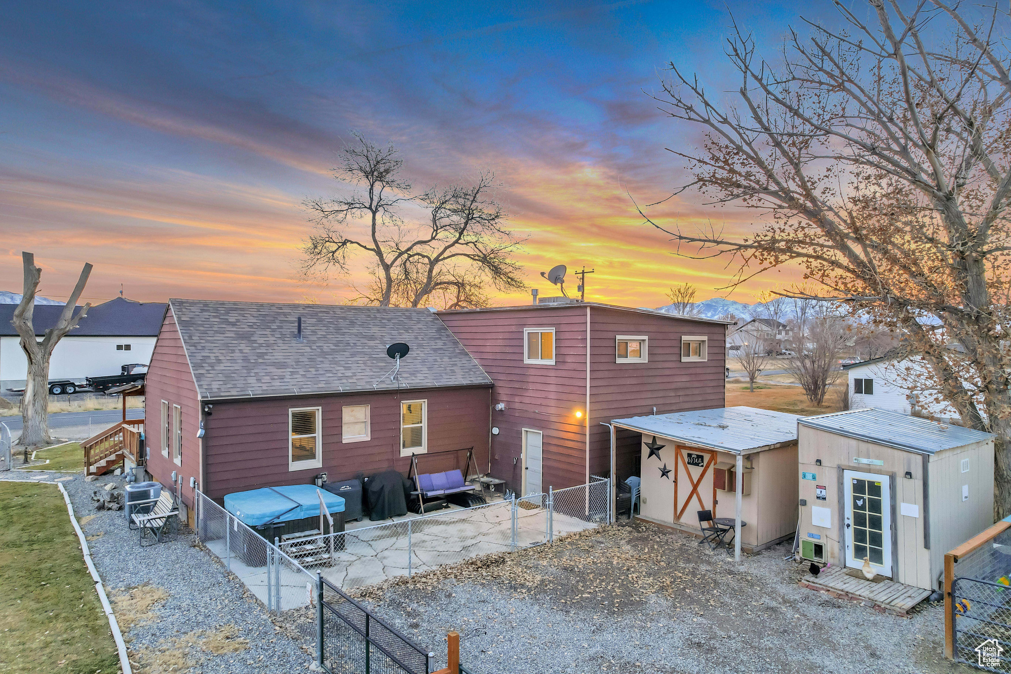 View of back house at dusk featuring sheds/chicken coop which are included