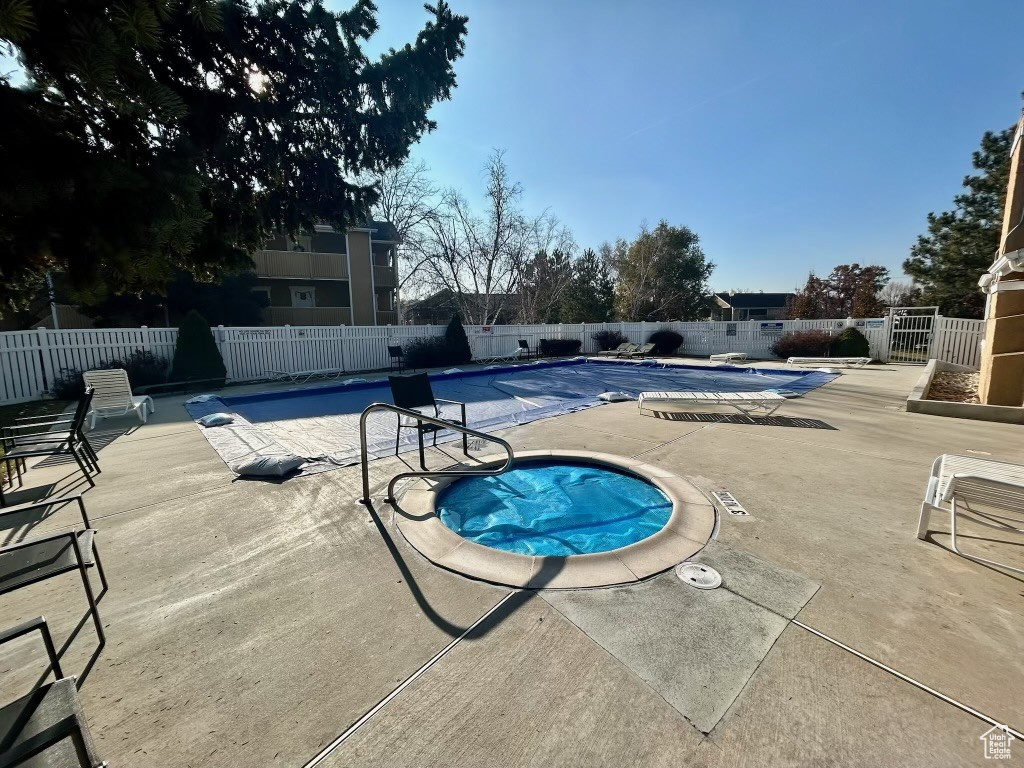 View of swimming pool featuring a community hot tub and a patio