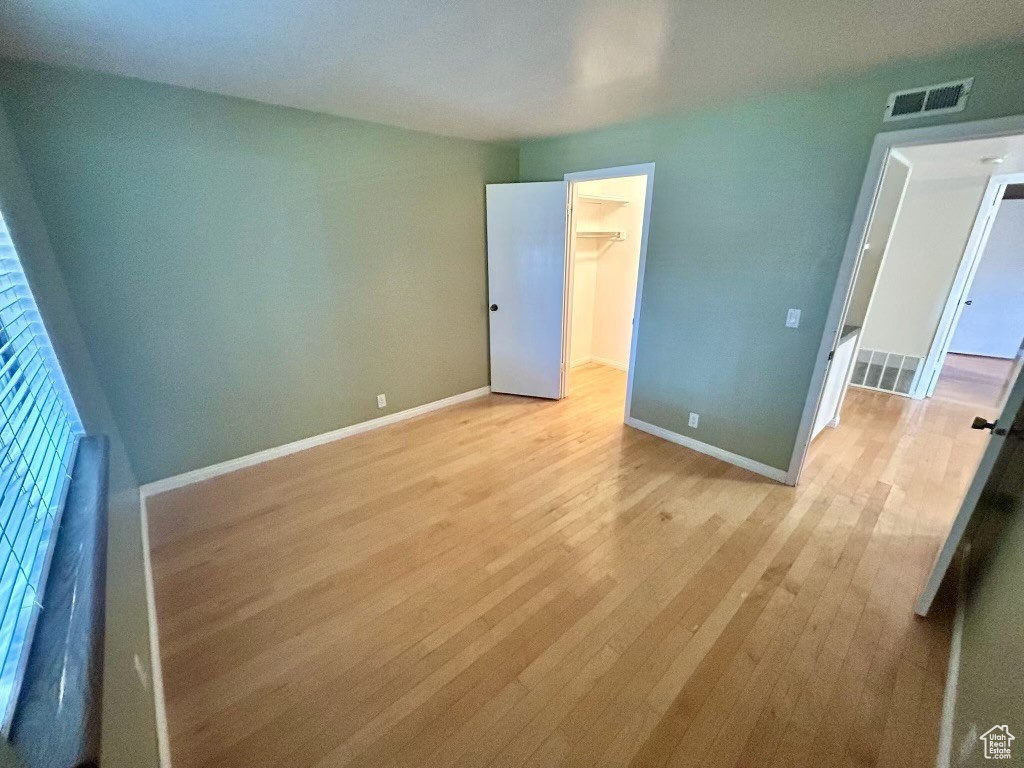 Unfurnished bedroom with light wood-type flooring, a spacious closet, and a closet