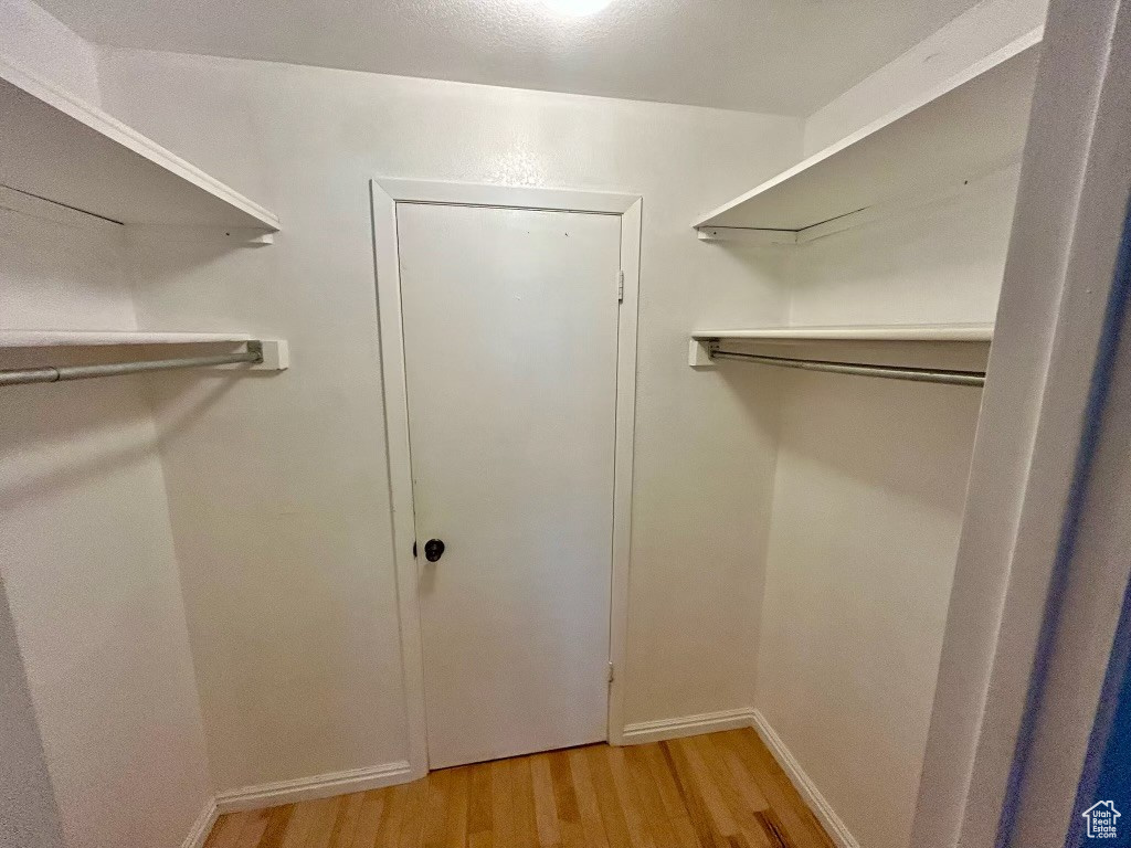 Walk in closet with light wood-type flooring