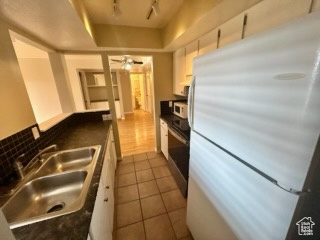 Kitchen featuring white appliances, white cabinets, sink, ceiling fan, and dark tile patterned floors