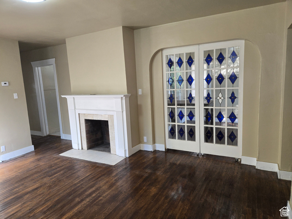 Unfurnished living room featuring dark hardwood / wood-style floors and a tiled fireplace