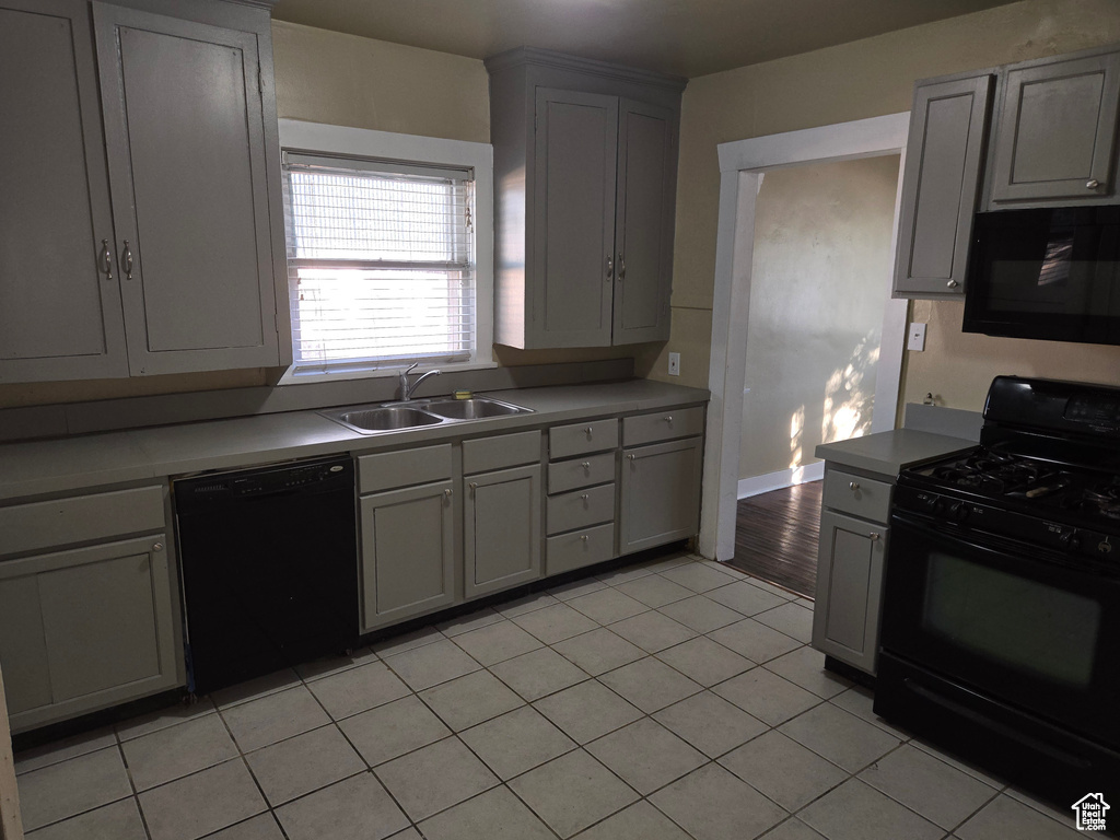 Kitchen with gray cabinetry, sink, light tile patterned floors, and black appliances