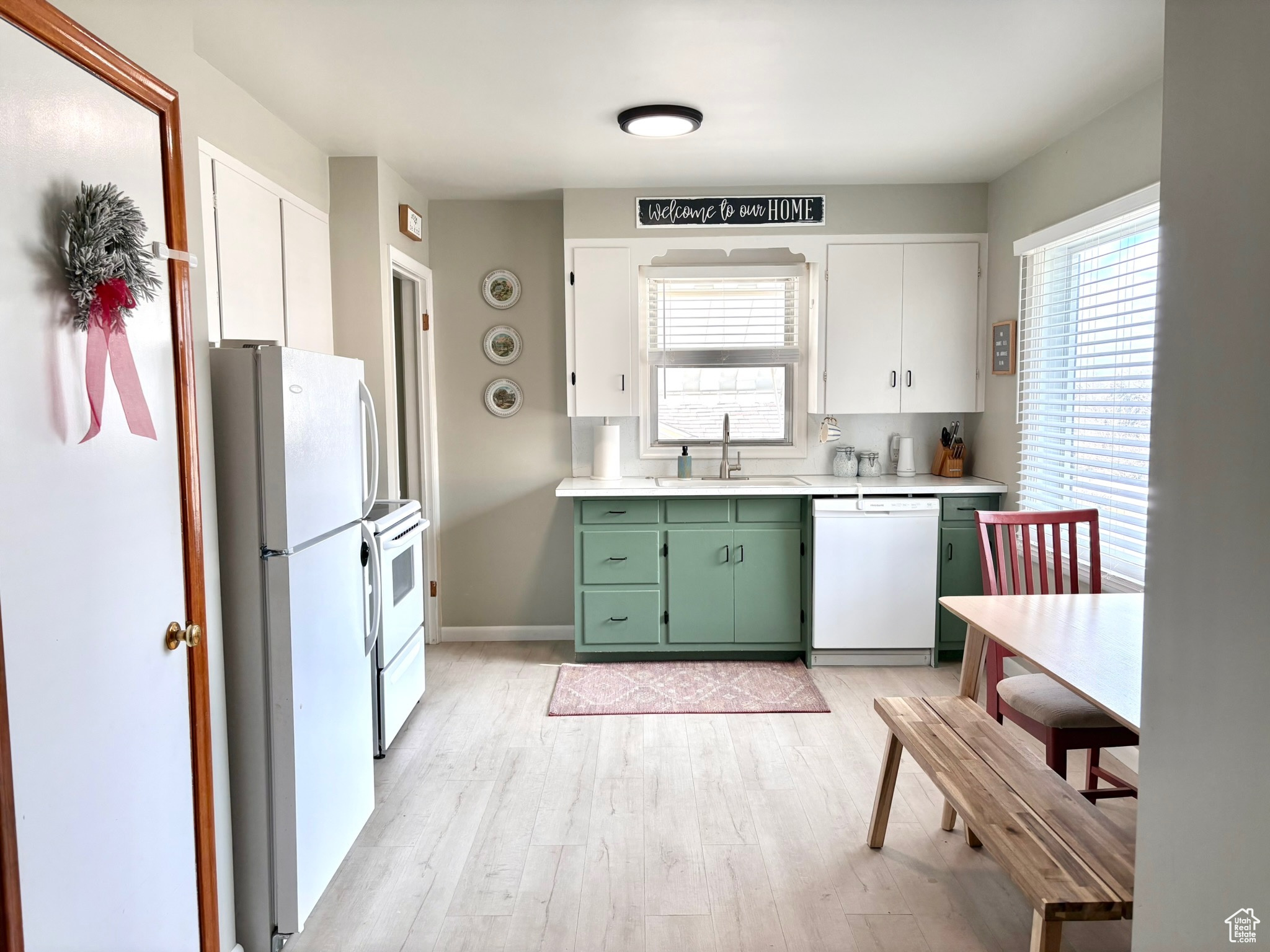 Kitchen with white appliances, sink, light hardwood / wood-style flooring, white cabinetry, and green cabinets