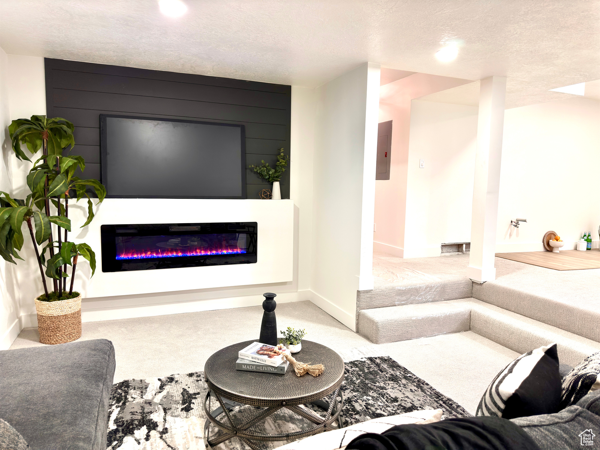 Carpeted living room featuring a textured ceiling, a fireplace, and electric panel