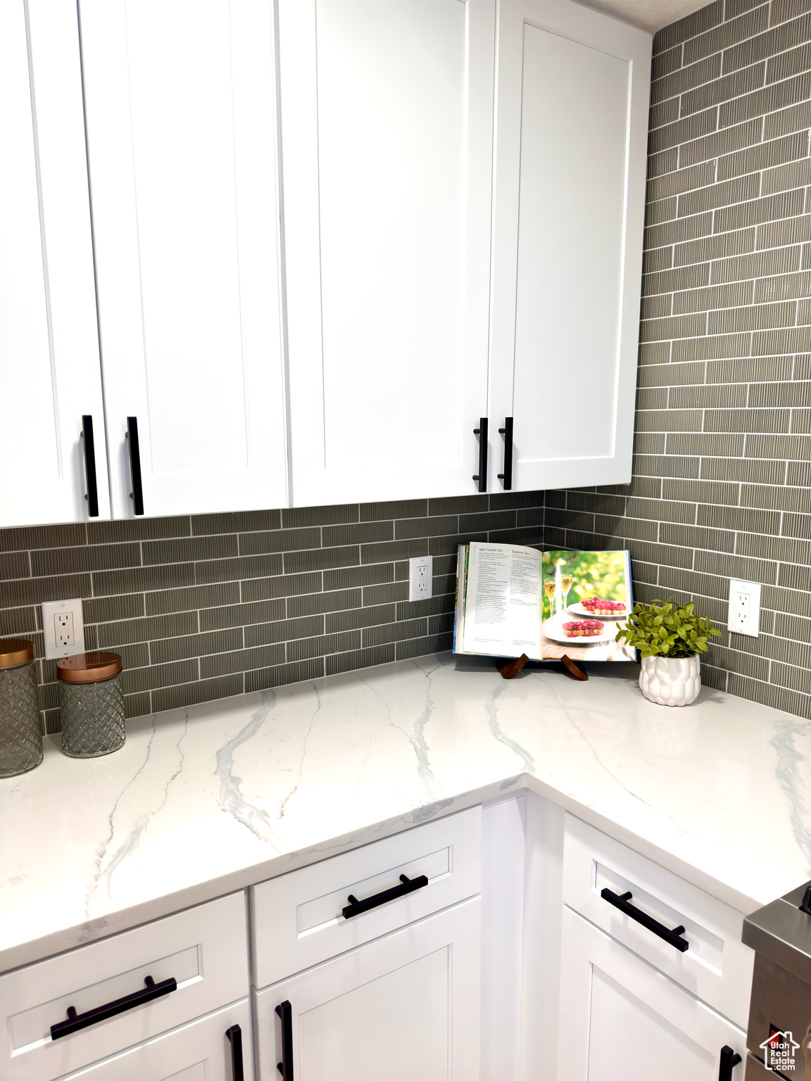 Kitchen featuring tasteful backsplash, white cabinetry, and light stone counters