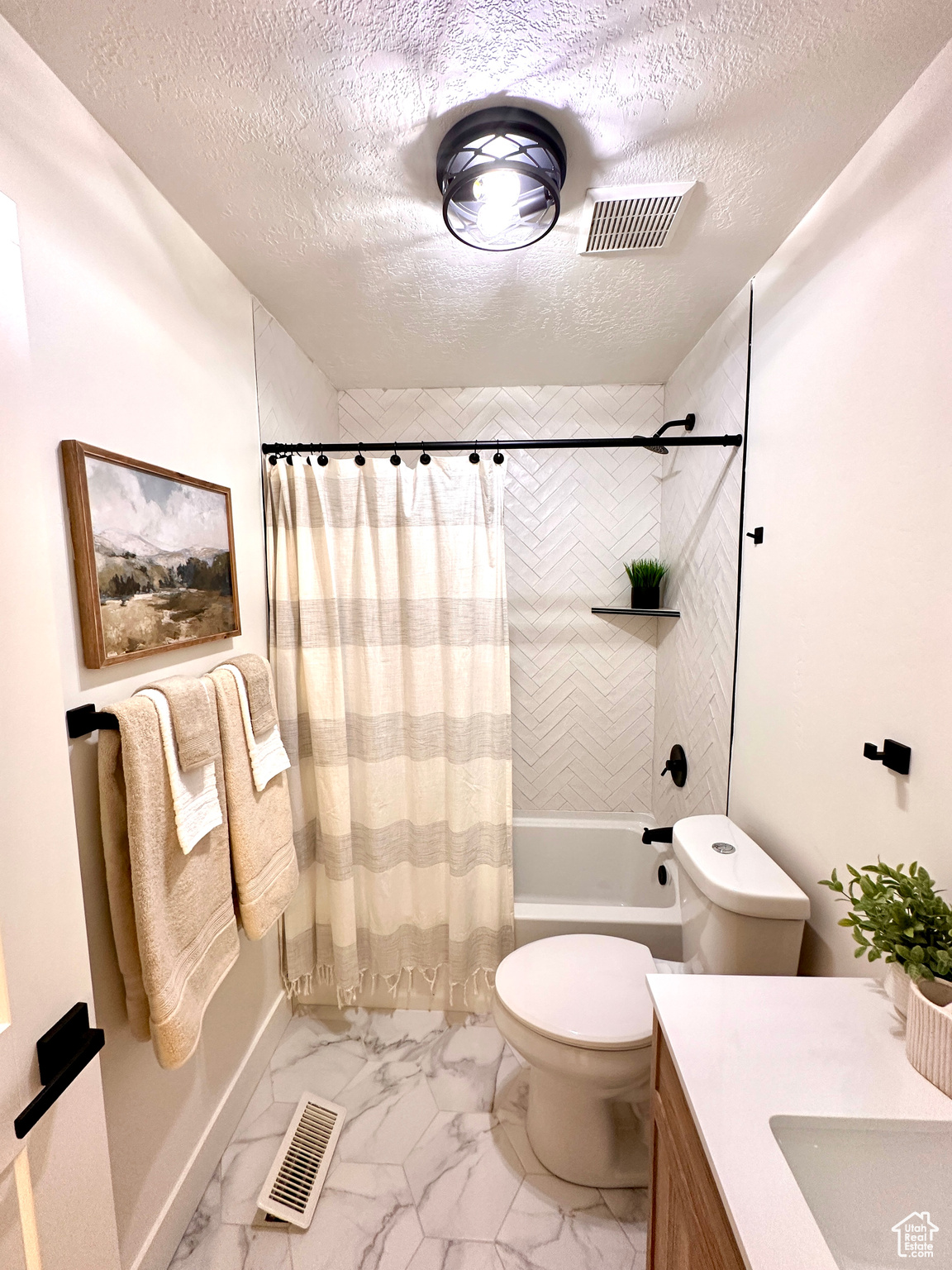 Full bathroom with shower / tub combo, vanity, a textured ceiling, and toilet