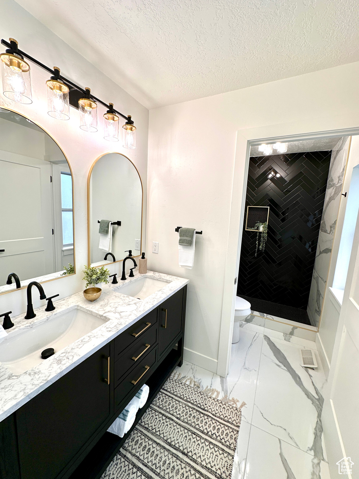 Bathroom featuring vanity, toilet, tiled shower, and a textured ceiling