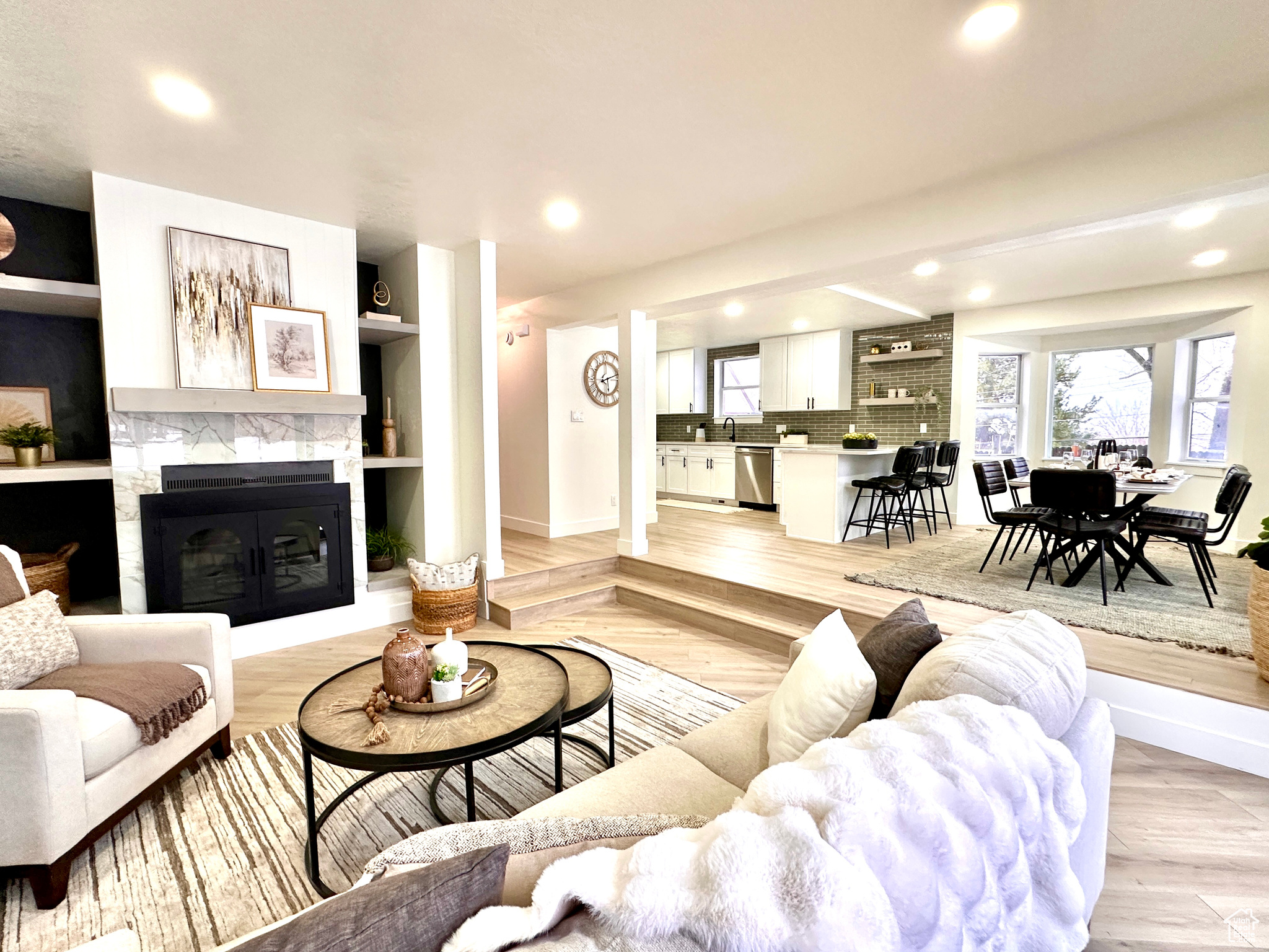 Living room featuring sink, built in shelves, light wood-type flooring, and a tiled fireplace