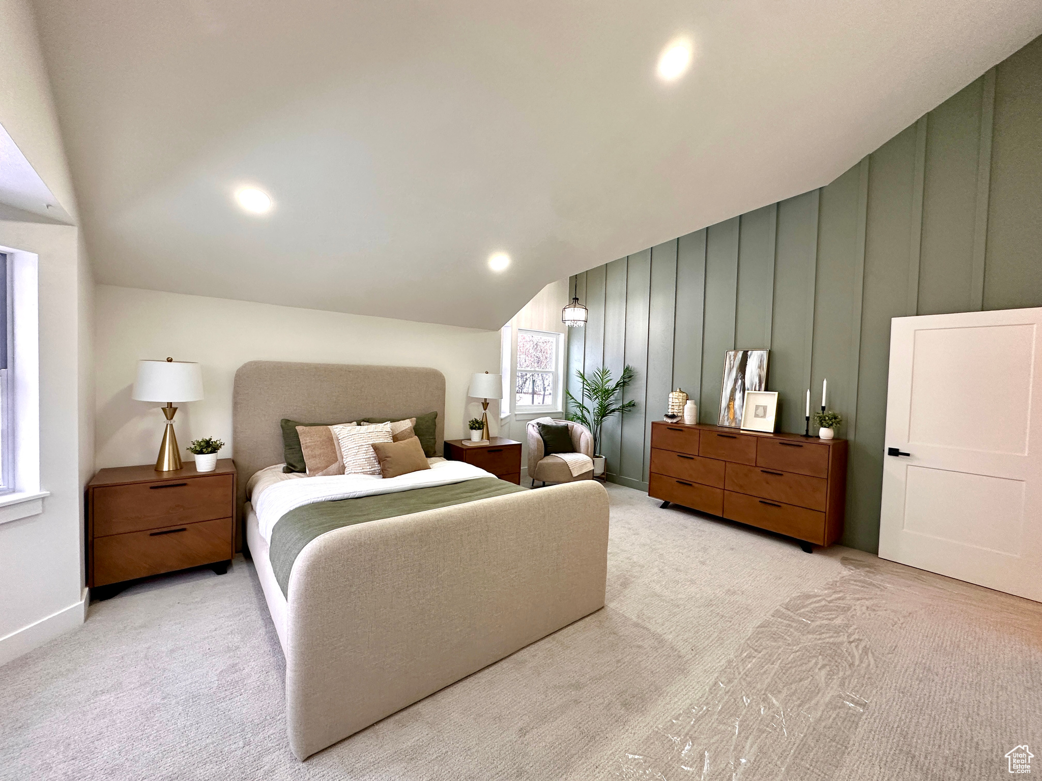 Carpeted bedroom with lofted ceiling and multiple windows