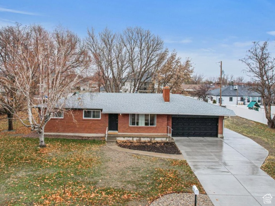 Single story home featuring a garage and a front lawn