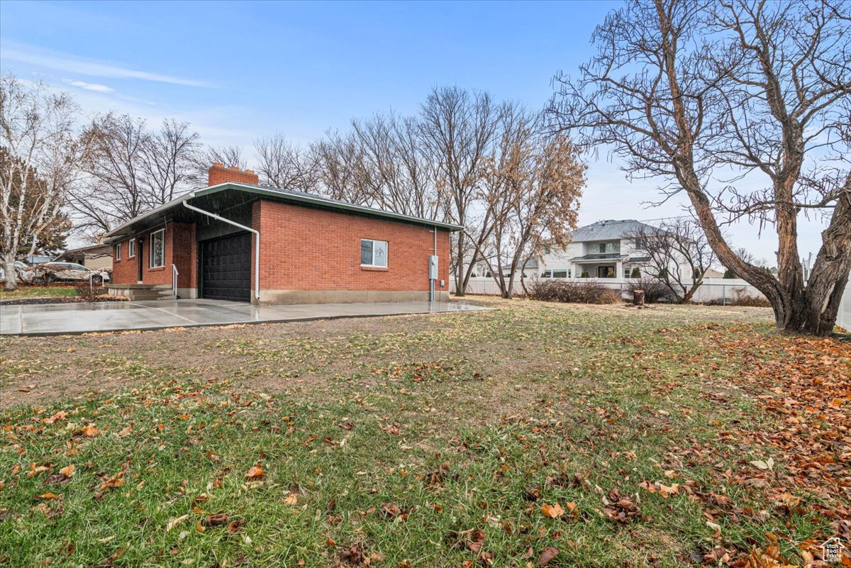 View of side of property with a yard, a garage, and a patio area