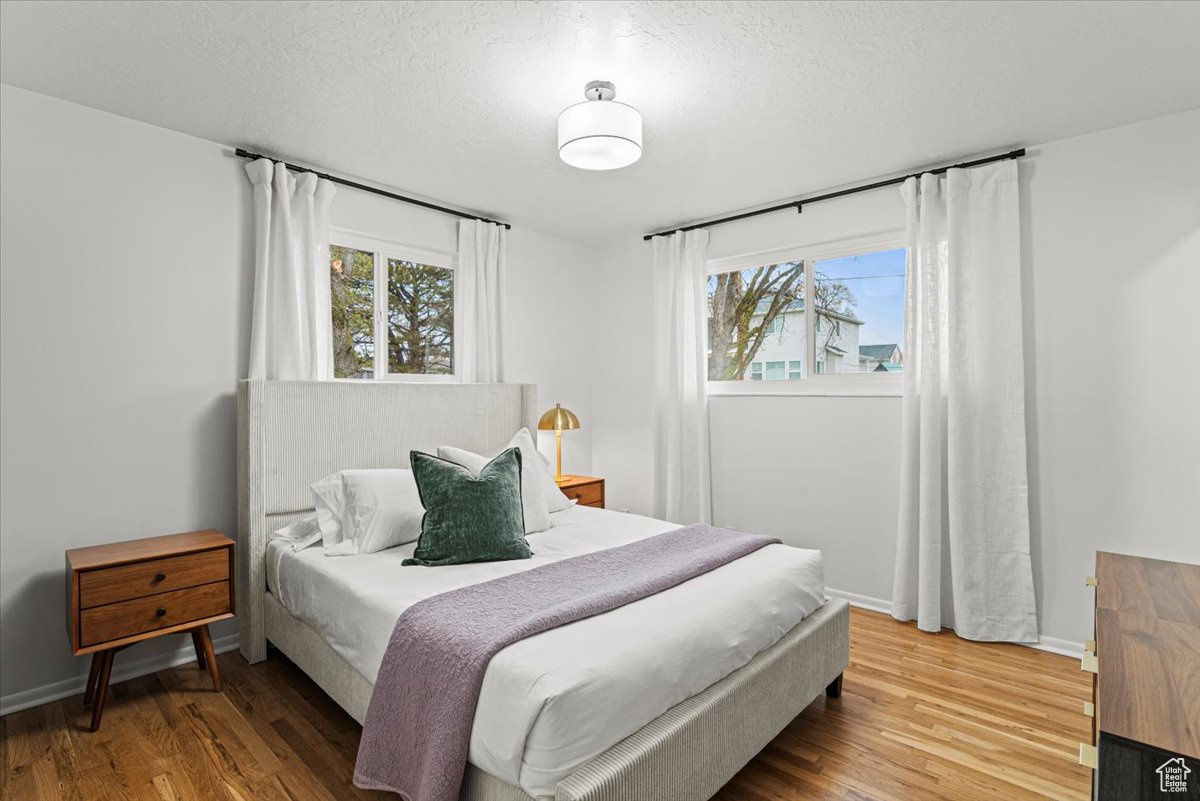 Bedroom with hardwood / wood floors, a textured ceiling, and multiple windows