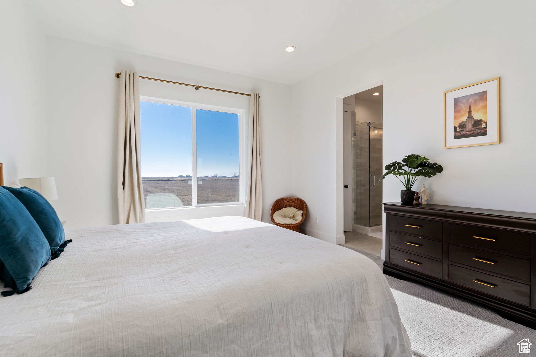 Bedroom with a water view, light colored carpet, and connected bathroom