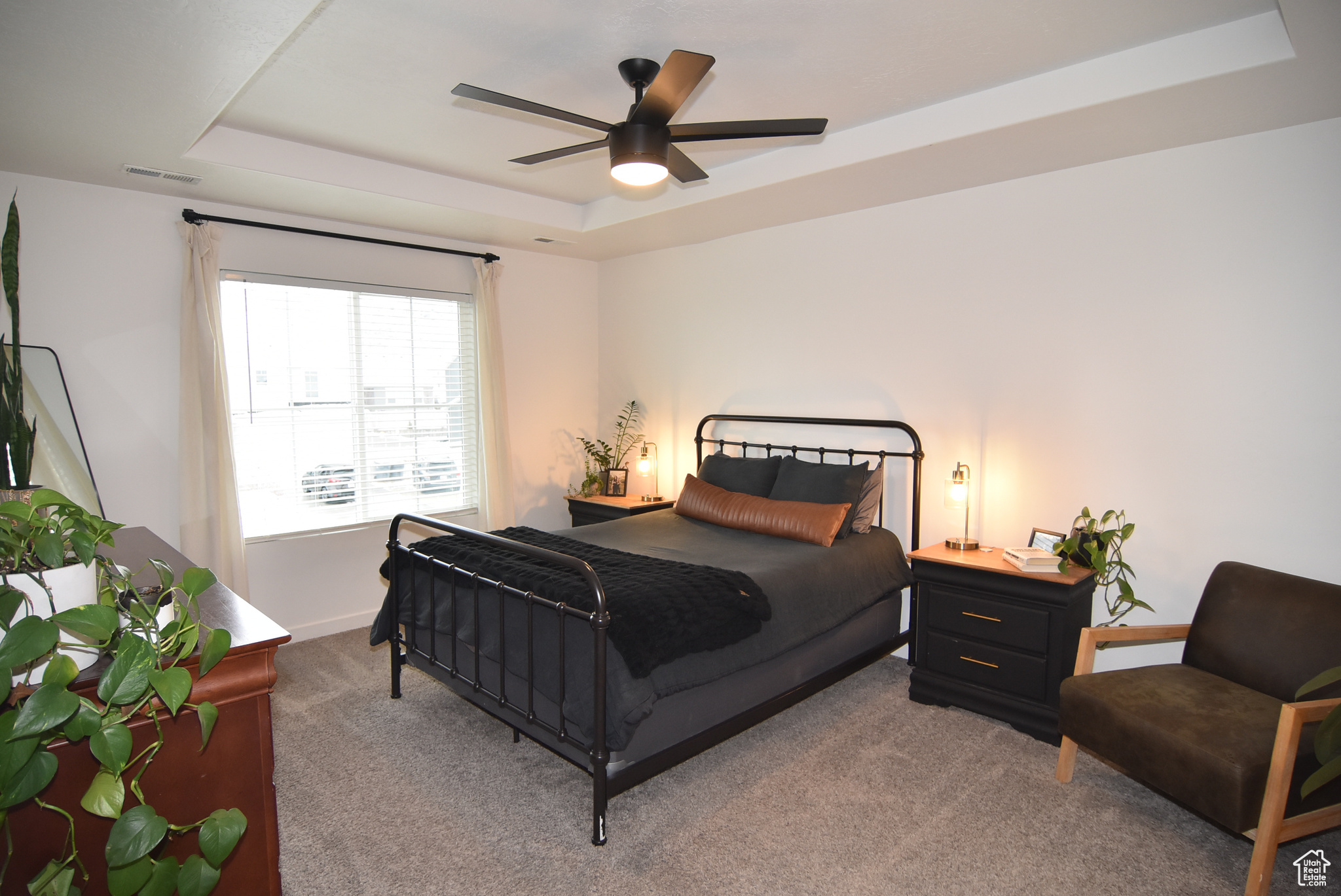 Carpeted Master bedroom featuring a raised ceiling and ceiling fan