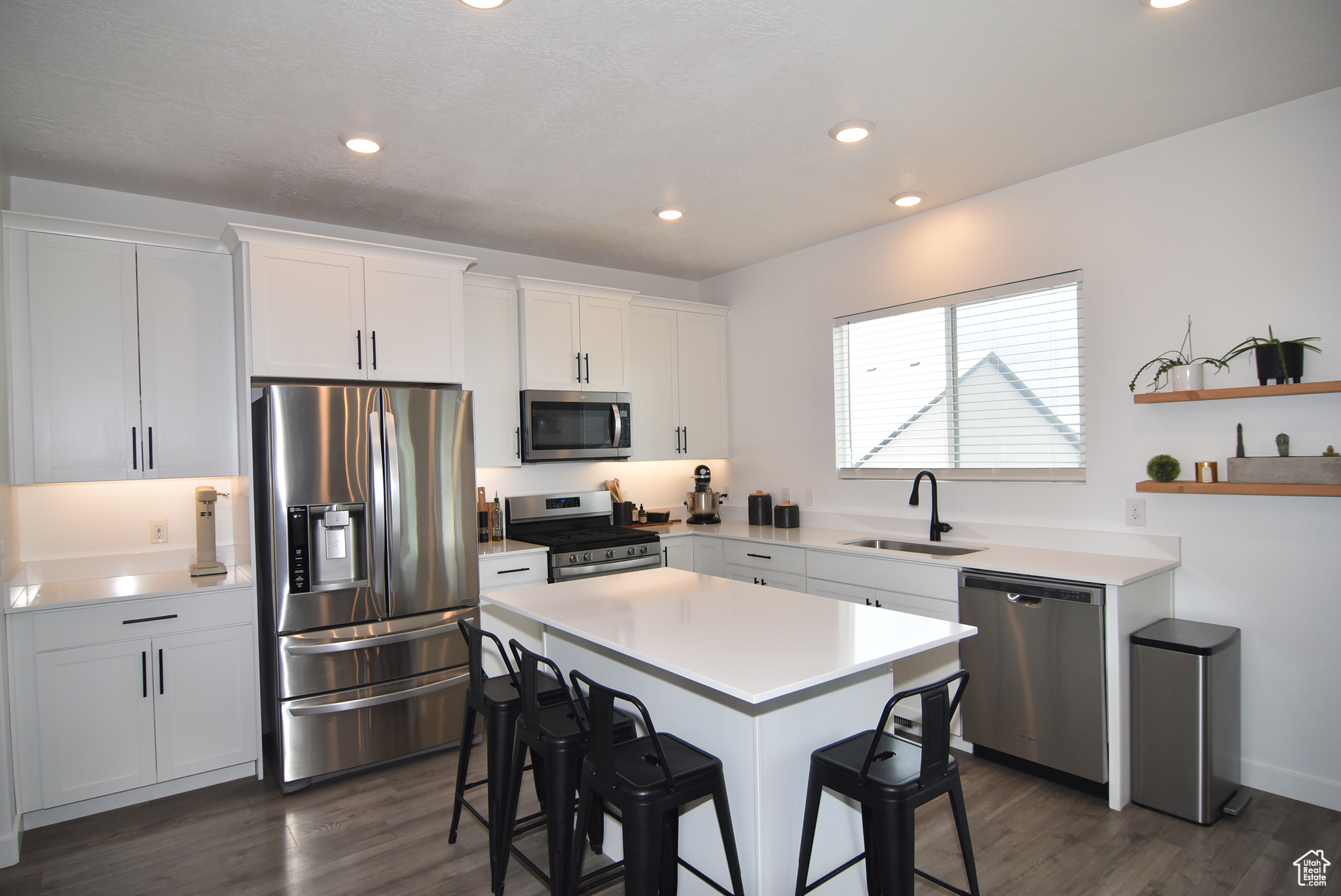 Kitchen featuring white cabinets, stainless steel appliances, a kitchen island, and sink