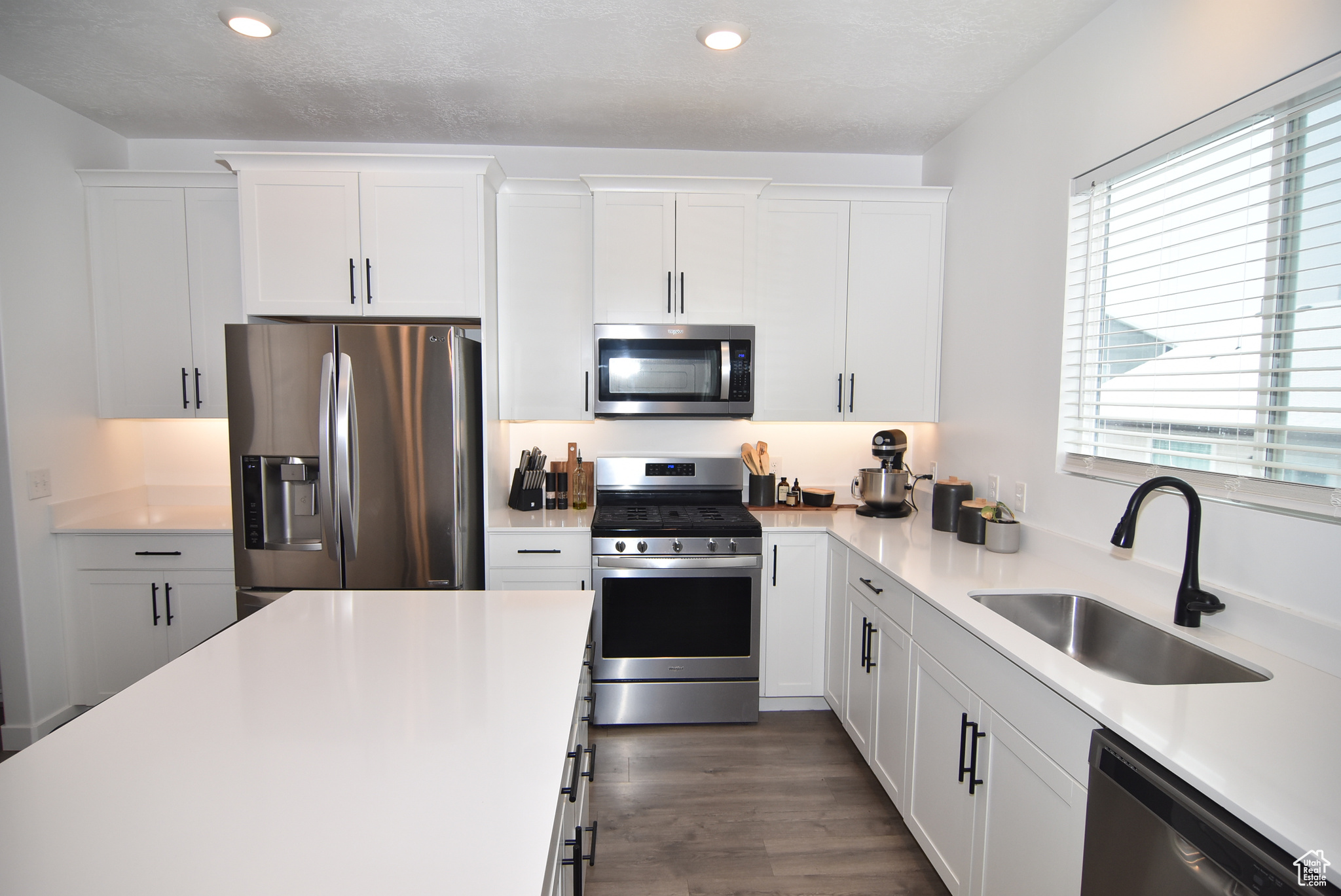 Kitchen featuring sink, white cabinets, and appliances with stainless steel finishes