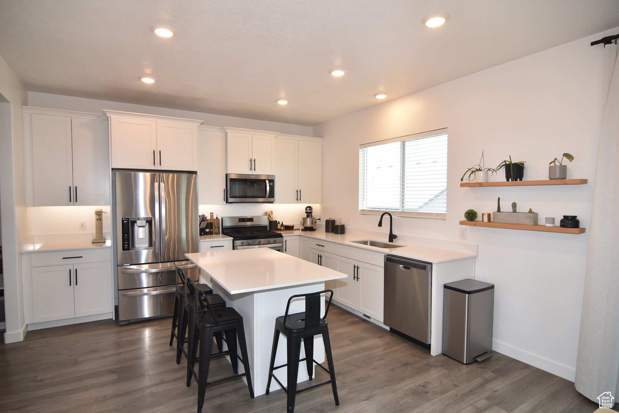 Kitchen with a kitchen bar, sink, white cabinets, and stainless-steel appliances