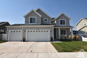 View of front of property featuring 3-car garage, covered front porch and front yard